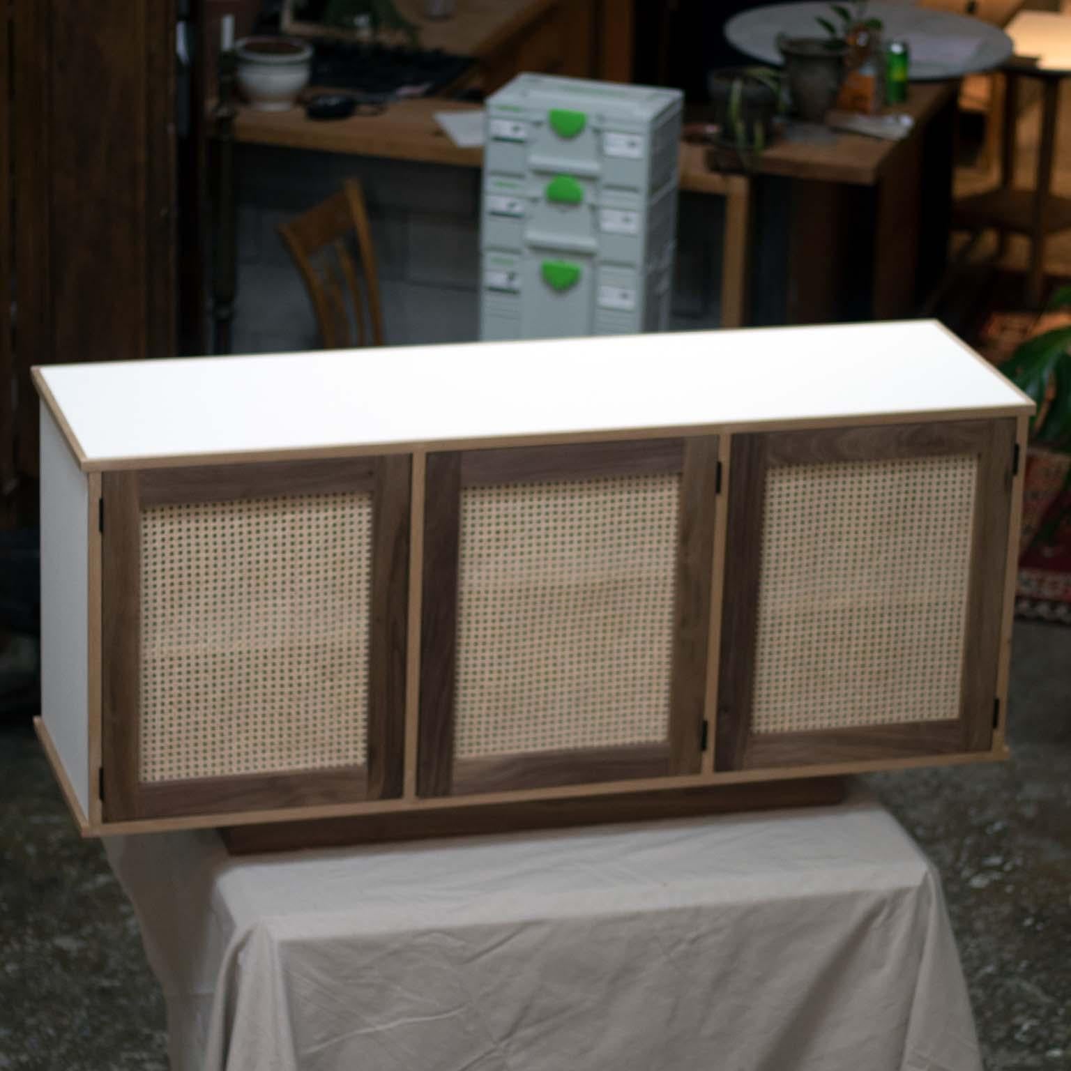 The Updike cabinet is perfect for someone looking for a modern piece of furniture with some vintage style.

The rattan doors allow this cabinet to be perfect for storing electronics that require a remote. 
Customers can specify dimensions, paint