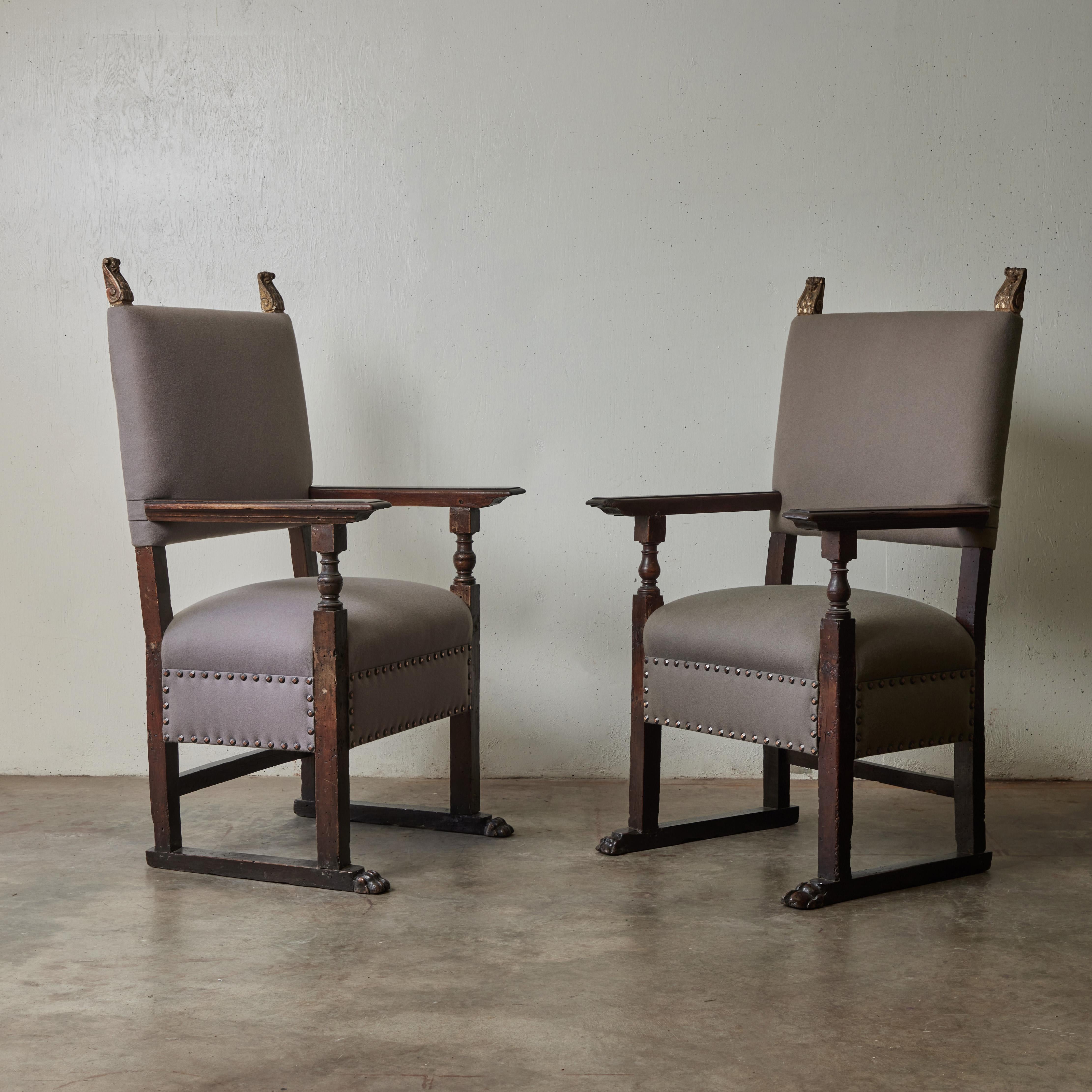 Pair of 18th-century Italian carved walnut arm chairs with gilt accenting and custom grey colored wool flanneled upholstery. A wonderful mix of Baroque elegance and modern restraint, the pair adds an updated touch of old-world glamour to any space.
