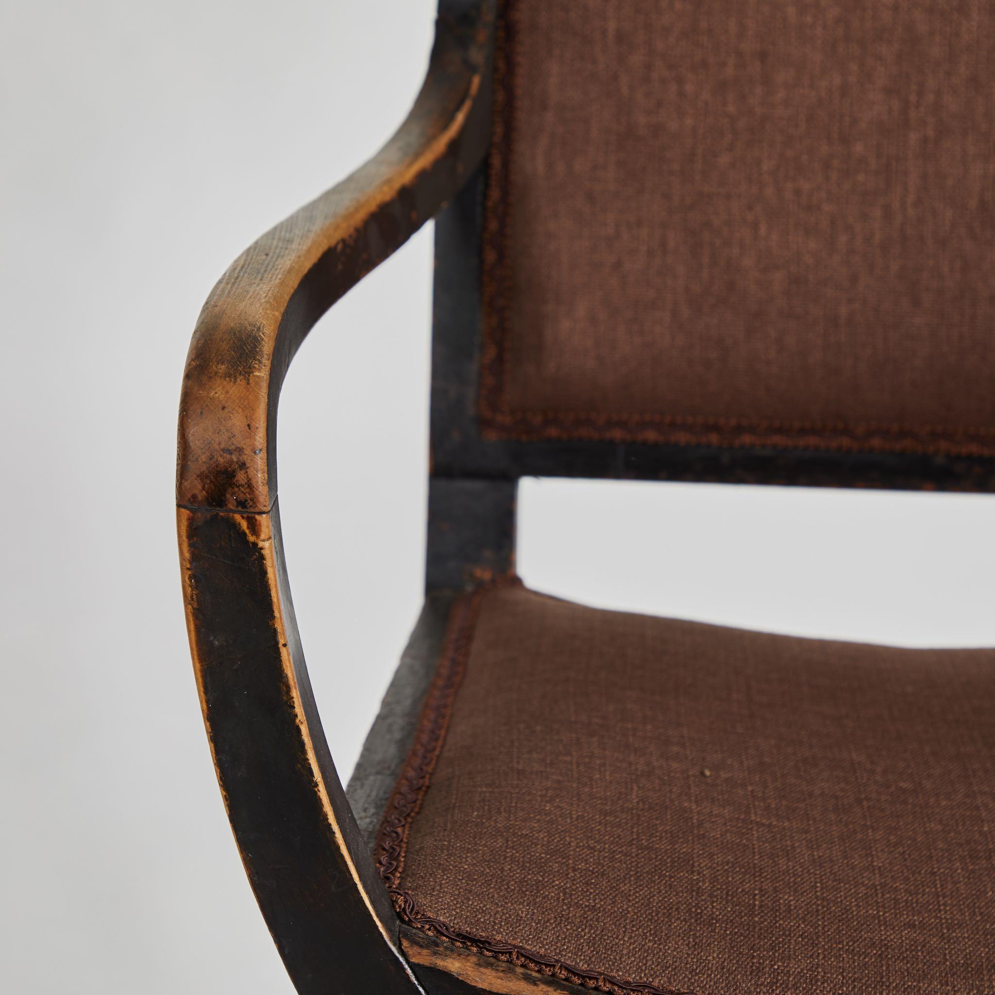 An upholstered armchair with great form displaying the original (worn) black painted finish.  England, circa 1860.