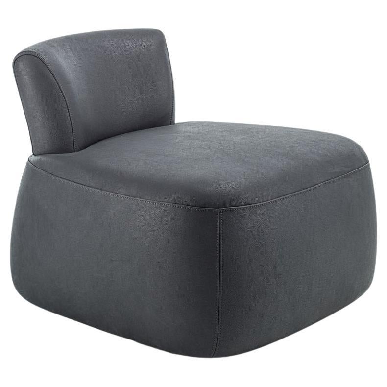 A solid wood backrest, both structural and decorative, distinguishes this upholstered armchair. Its solid, flowing wooden frame connects to the upholstered seat, creating a visual and functional relationship between the two padded volumes. The