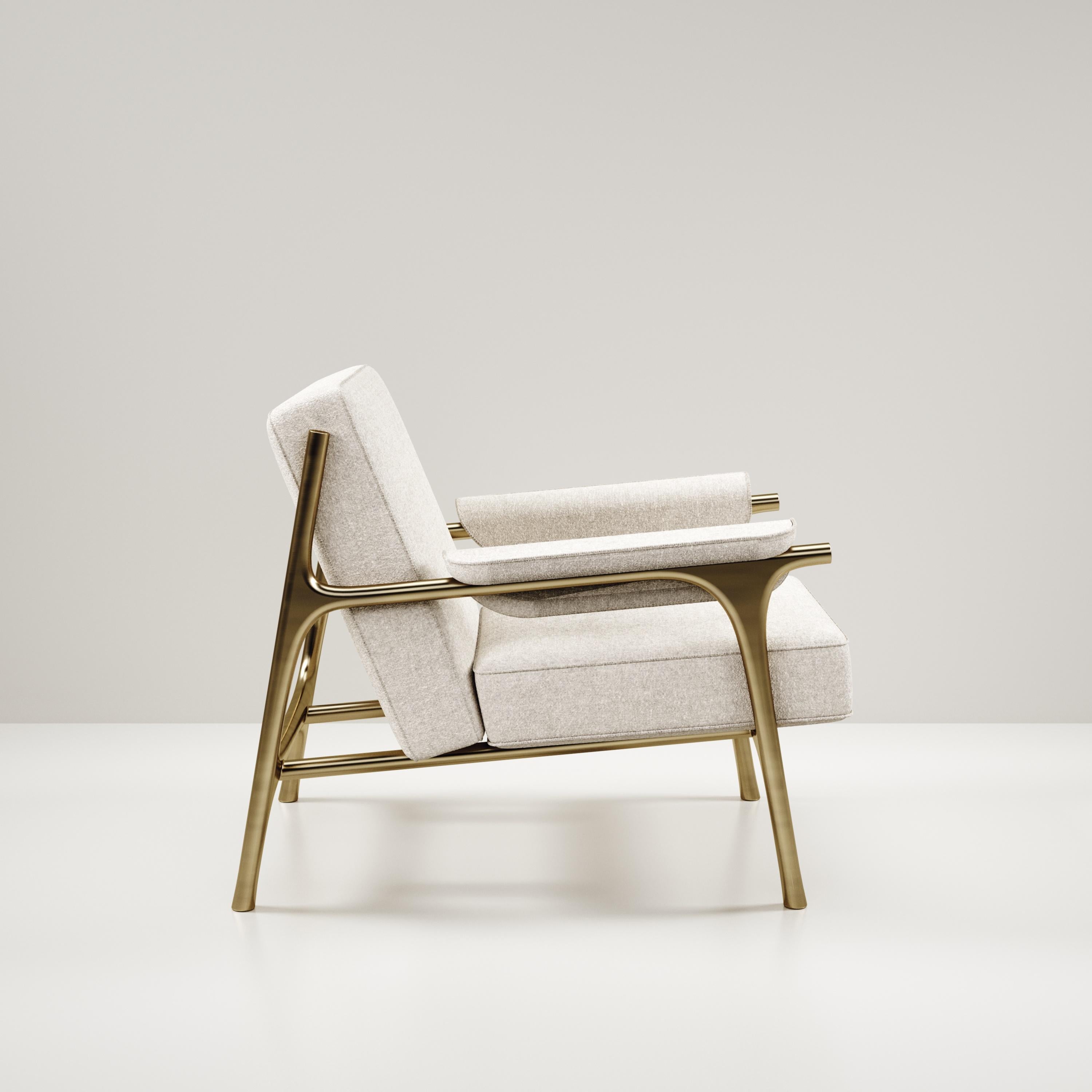 The Ramo armchair by R & Y Augousti is an elegant and versatile piece. The upholstered piece in cream Pierre Frey fabric provides comfort while retaining a unique aesthetic with the bronze-patina brass frame and details. This listing is priced for