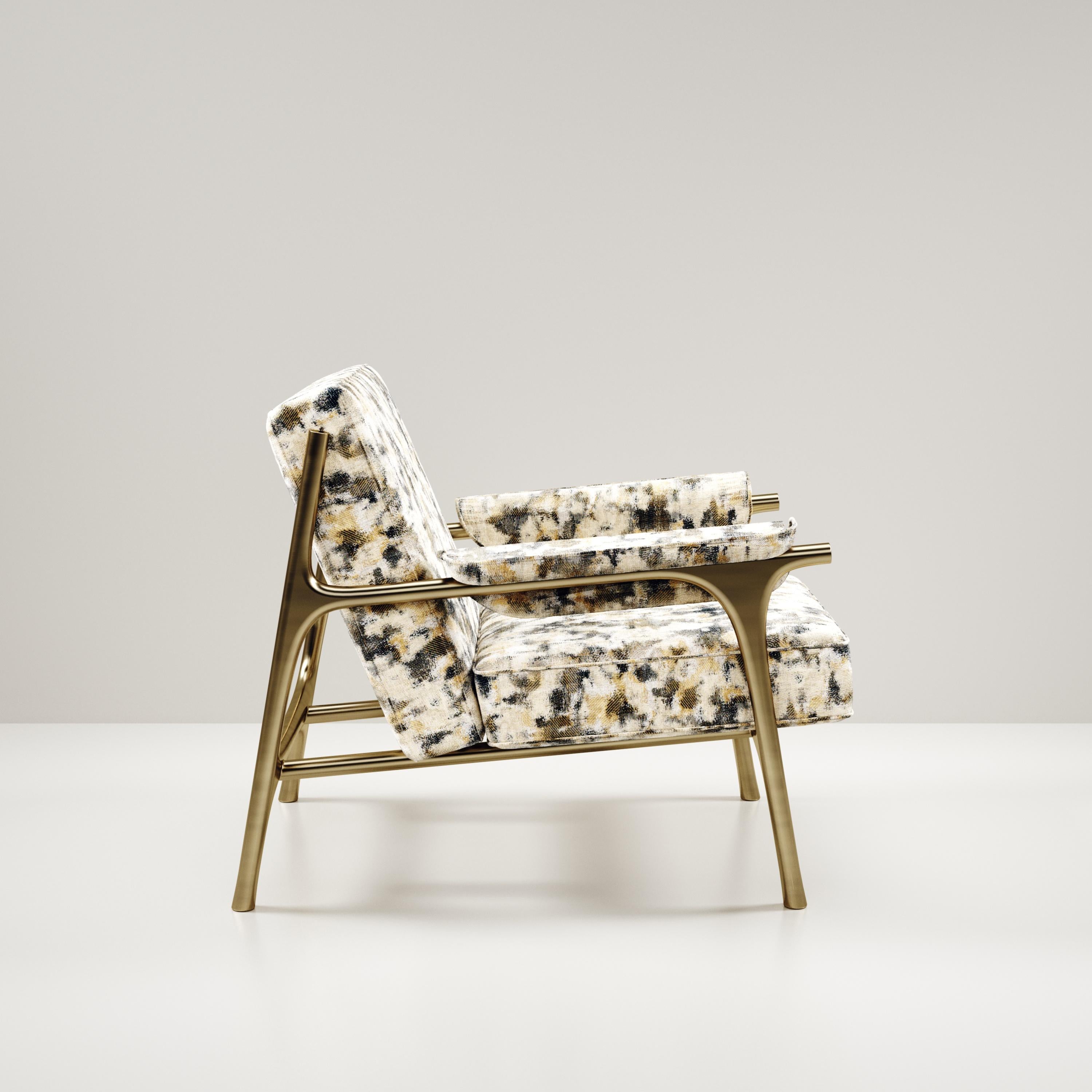 The Ramo Armchair by R & Y Augousti is an elegant and versatile piece. The upholstered piece in camouflage Pierre Frey fabric provides comfort while retaining a unique aesthetic with the bronze-patina brass frame and details. This listing is priced