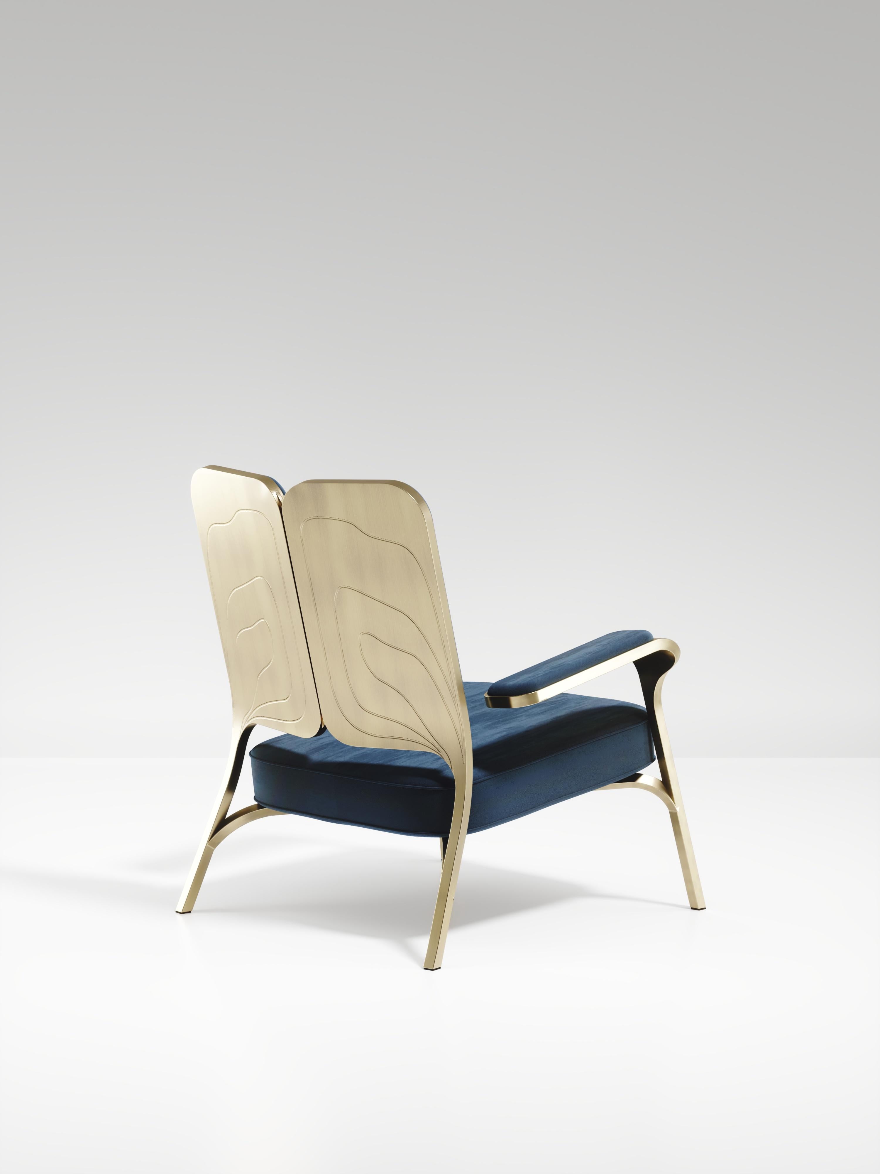 The Gingko armchair by R & Y Augousti is an elegant and whimsical piece. The blue velvet upholstered piece provides comfort while exuding a playful aesthetic in its abstract nod to a butterfly with the form of its backrest and intricate engraving