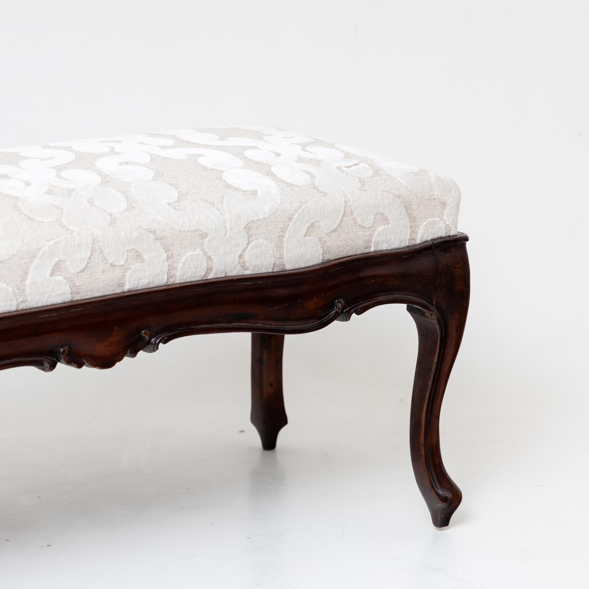 Small upholstered bench in baroque style with a multiple curved frame on elegant s-legs. This bench seats two people and has been reupholstered in a high quality cream and white fabric decorated with raised C-frame decoration. Frame height: 39 cm.