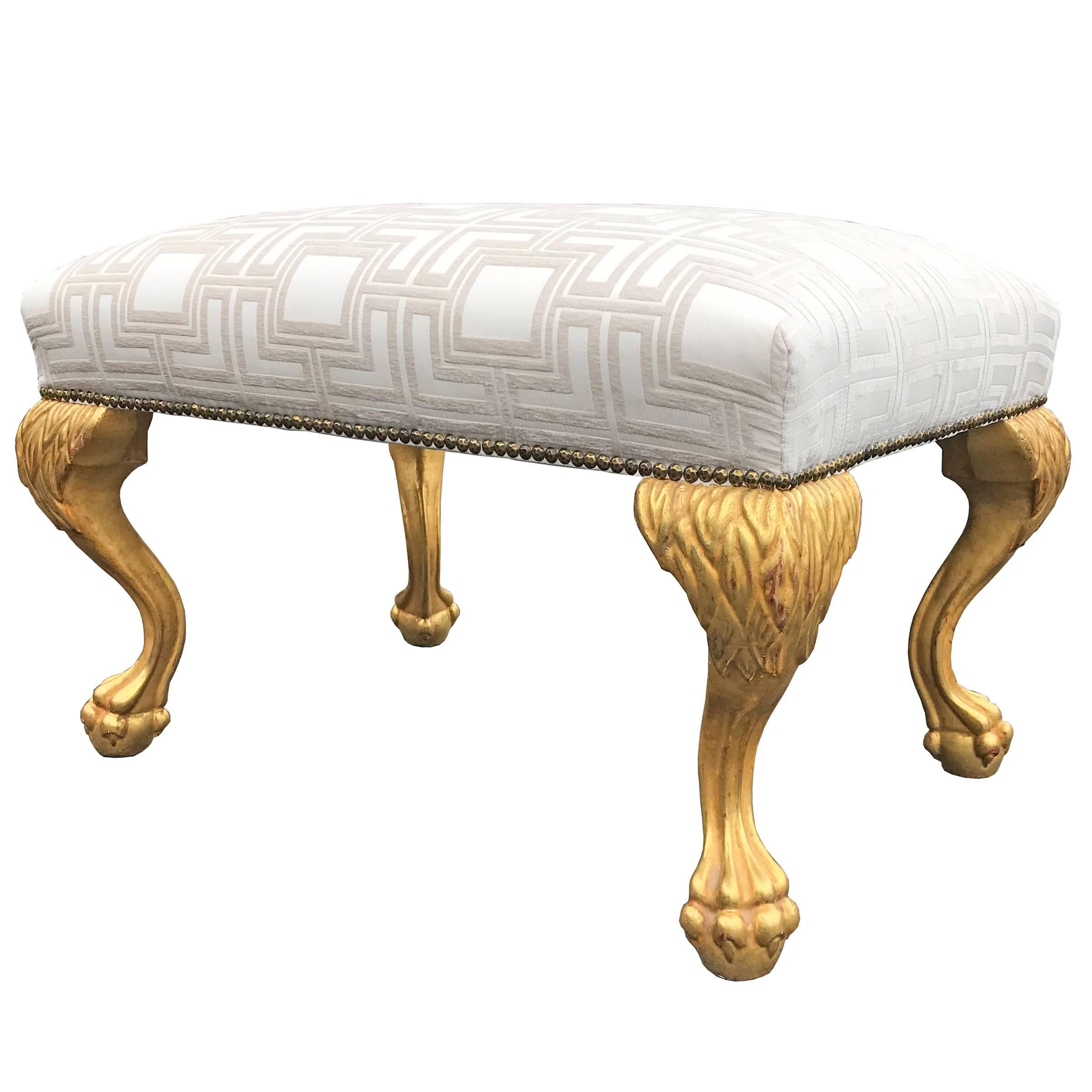 A 21st century American water giltwood upholstered bench with fantastic furry lion legs with paw and ball feet. The gilding is the done the correct way, with a red clay base and gold leaf applied with water on top. The upholstery is a geometric