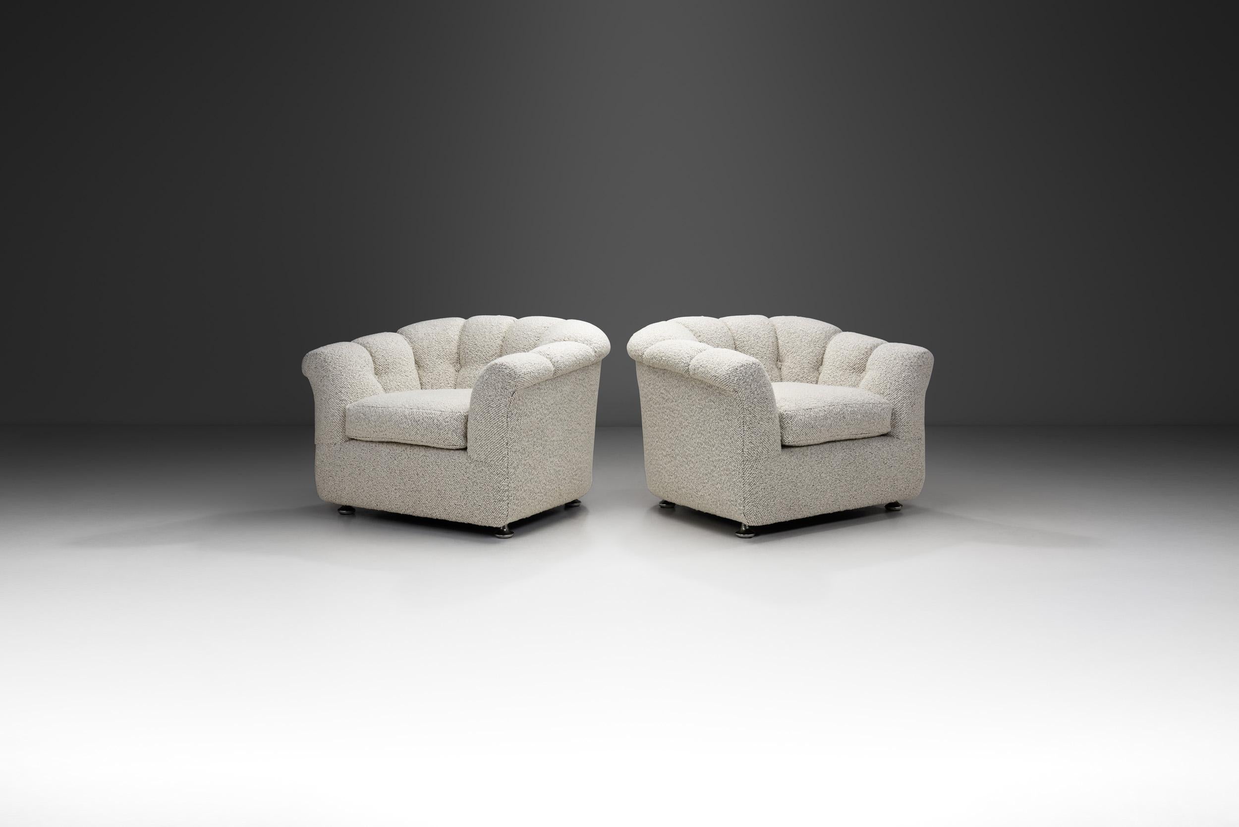 This pair of club chairs from the 1970s stands as a captivating blend of timeless design influences. Fully upholstered in a luxurious white bouclé fabric, these chairs epitomize the essence of comfort and style. Their scalloped bodies exude a