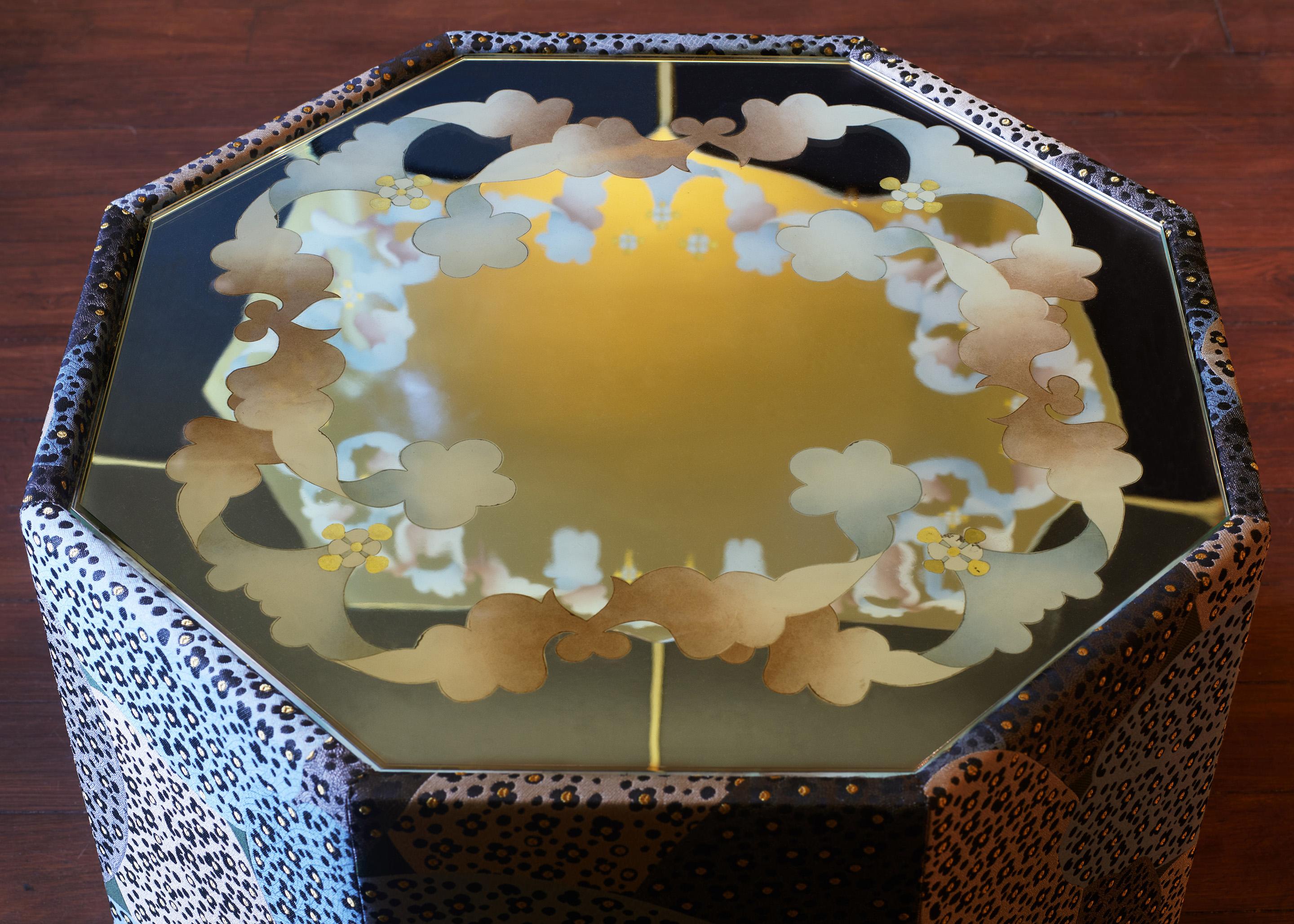 Table octogonale en bois recouverte d'un tissu jacquard Leopara (100 % polyester) et d'un plateau miroir décoré selon la technique du fixé-sous-verre.  par l'Atelier Duchemin.
Leopara : tissu jacquard conçu et développé par Pierre Marie Studio,