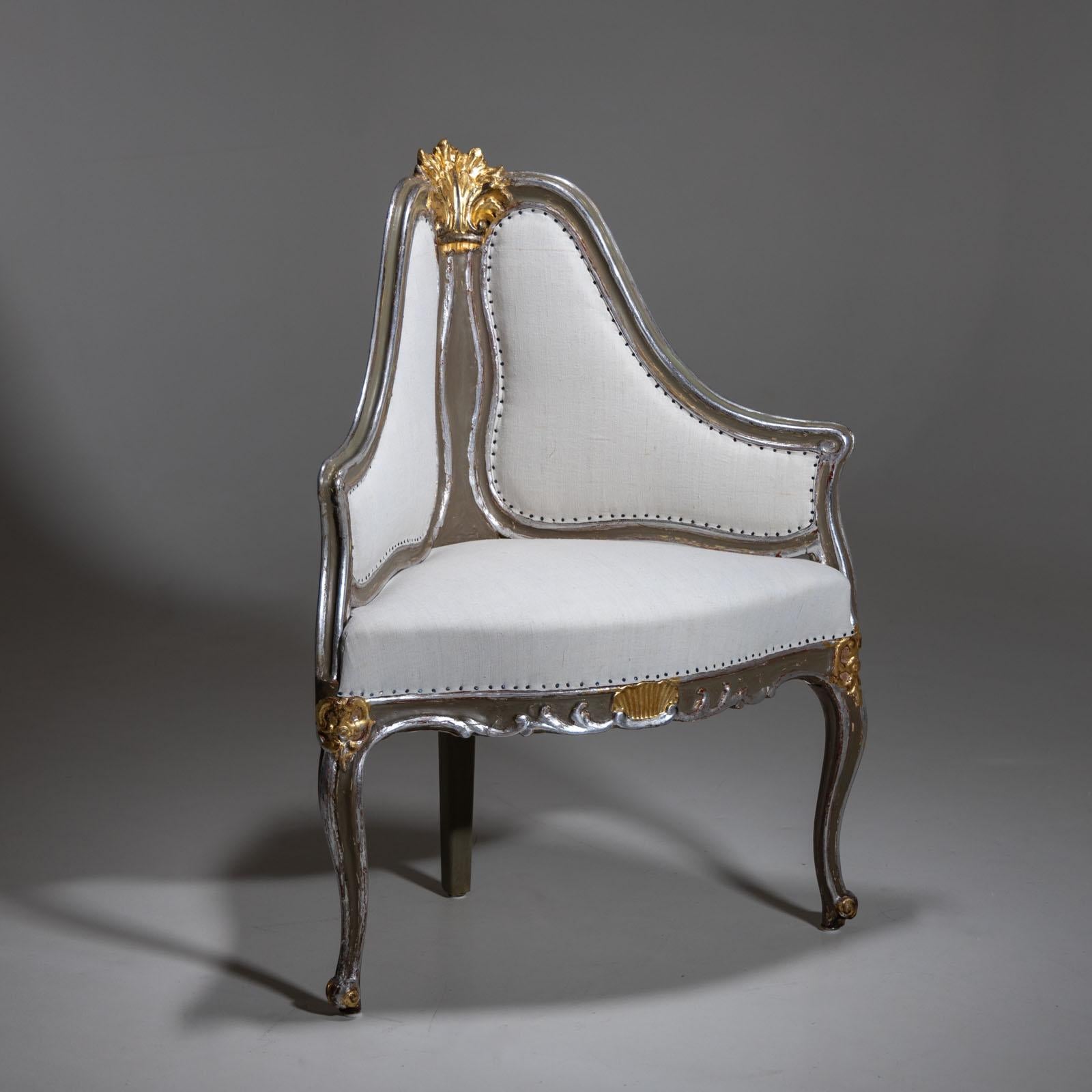 An armchair designed as a corner solution on three S-shaped legs with a wavy frame and shell decoration. The high curved backrest is upholstered and is crowned by another carved leaf ornament. The armchair is newly painted and patinated in gold and