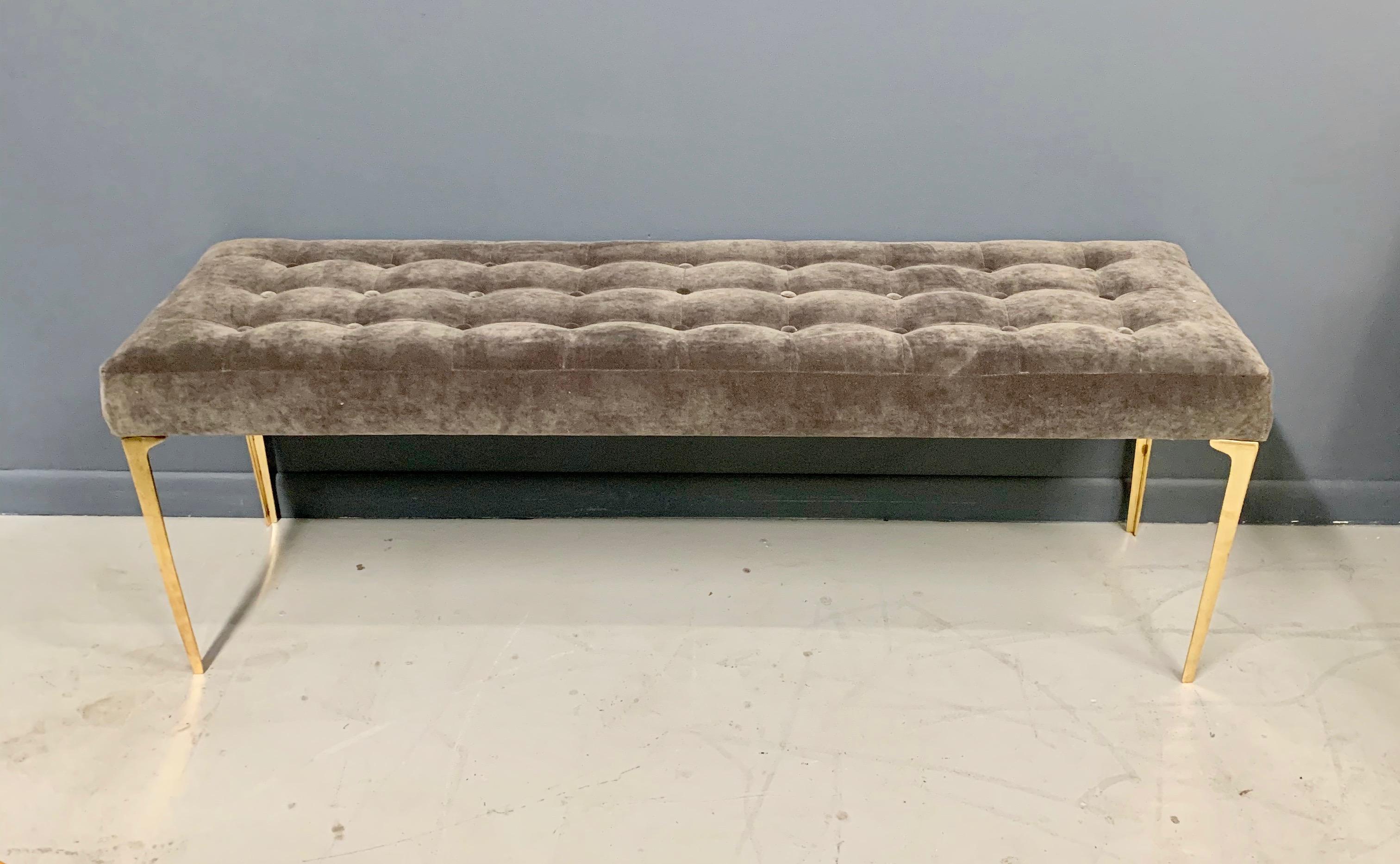 Beautifully upholstered long bench with tapered brass legs. This bench has a lovely grey velvet with buttons.