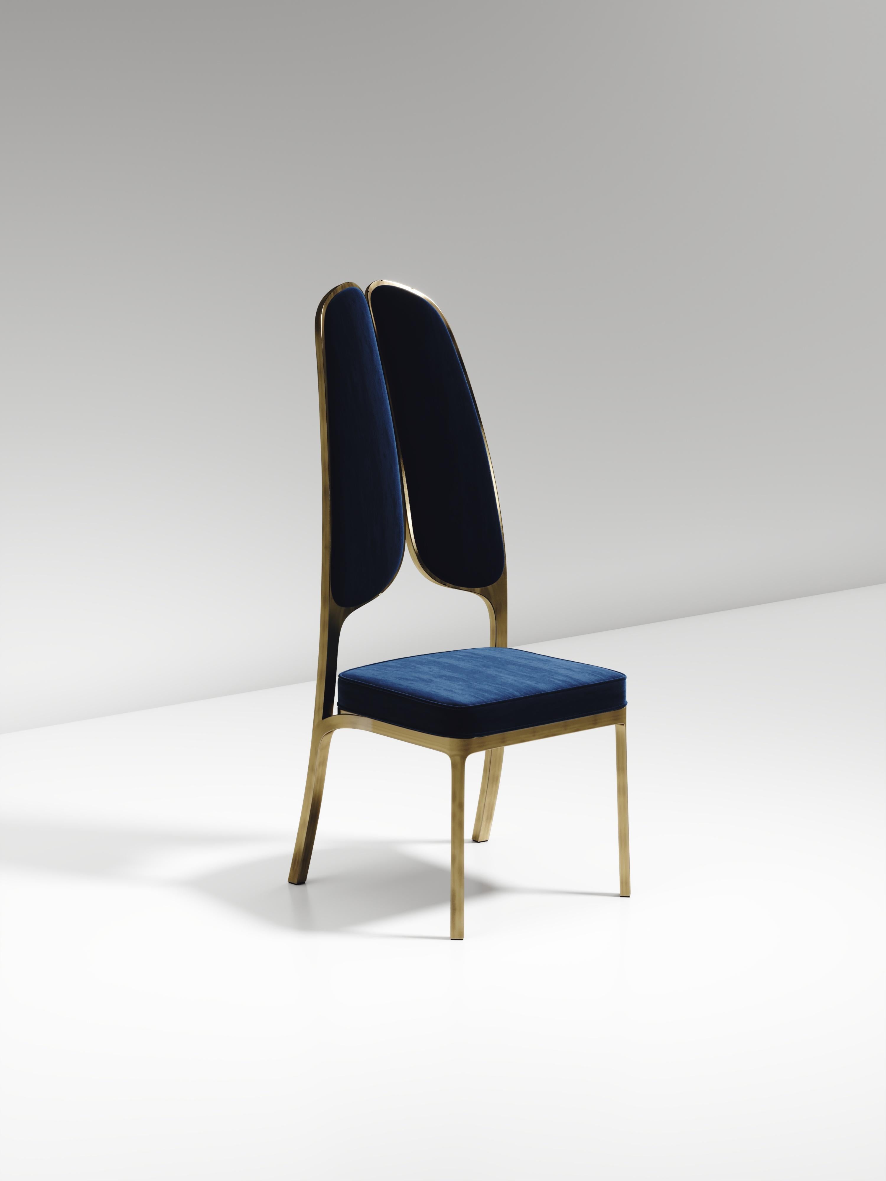 The Gingko dining chair by R & Y Augousti is an elegant and whimsical piece. The blue velvet upholstered piece provides comfort while exuding a playful aesthetic in its abstract nod to a butterfly with the form of its backrest. Available in an
