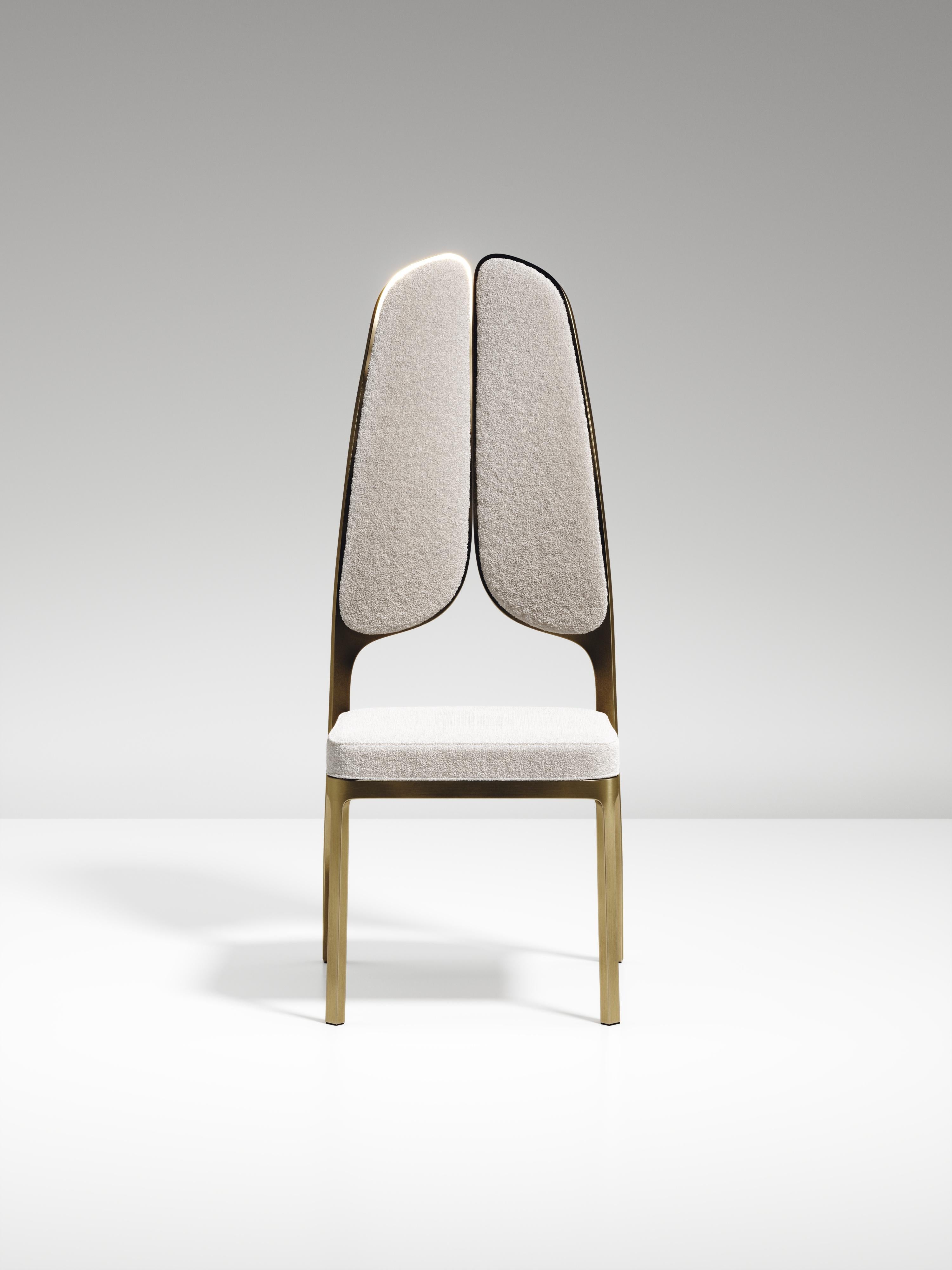 The Gingko dining chair by R & Y Augousti is an elegant and whimsical piece. The cream linen upholstered piece provides comfort while exuding a playful aesthetic in its abstract nod to a butterfly with the form of its backrest. Available in an