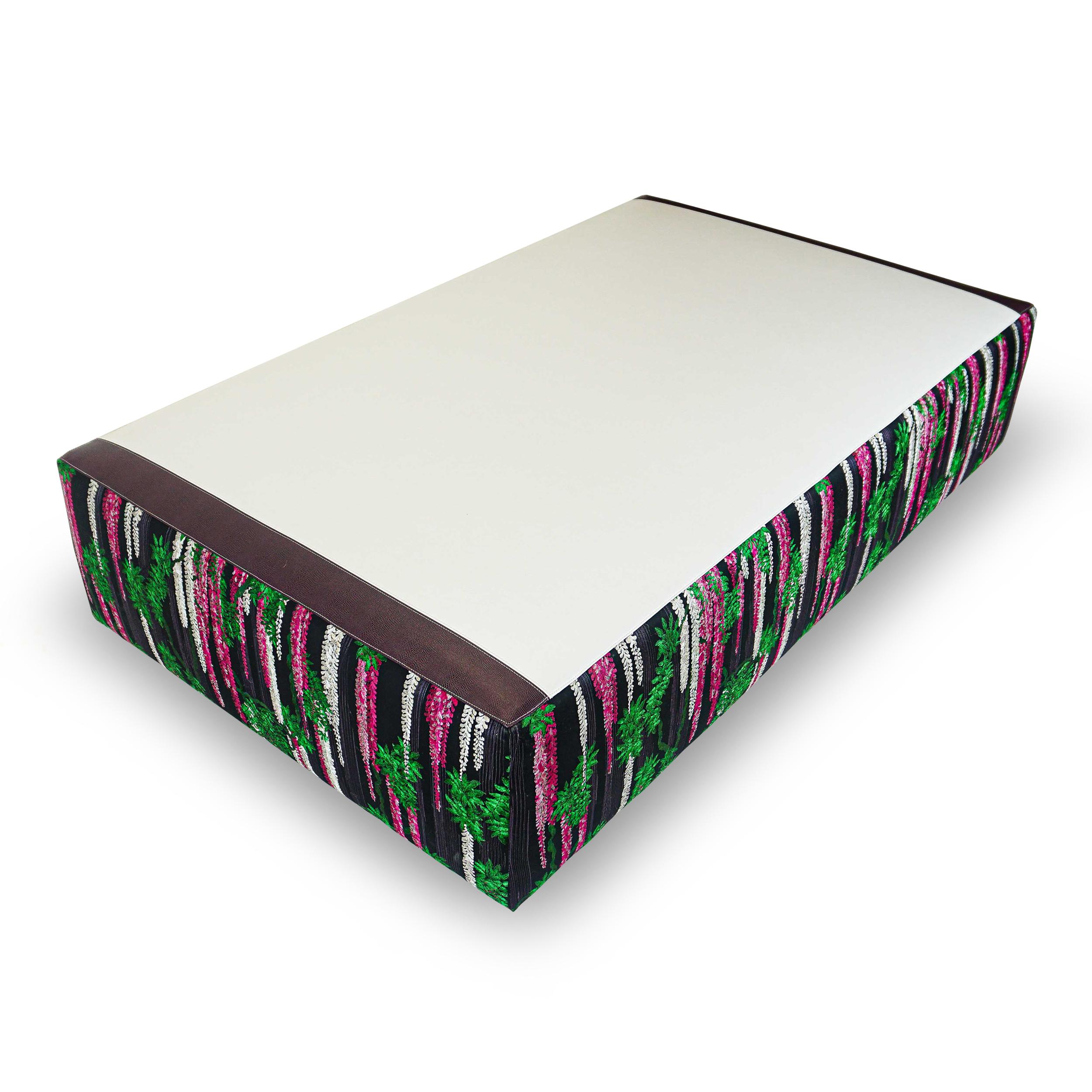 This oversize ottoman is upholstered in a faux white leather top with a rich plum accent strip at two ends. A glorious Christian Lacroix embroidery of richly shaded trailing wisteria juxtaposed against a striking graphite hued, pure cotton ground