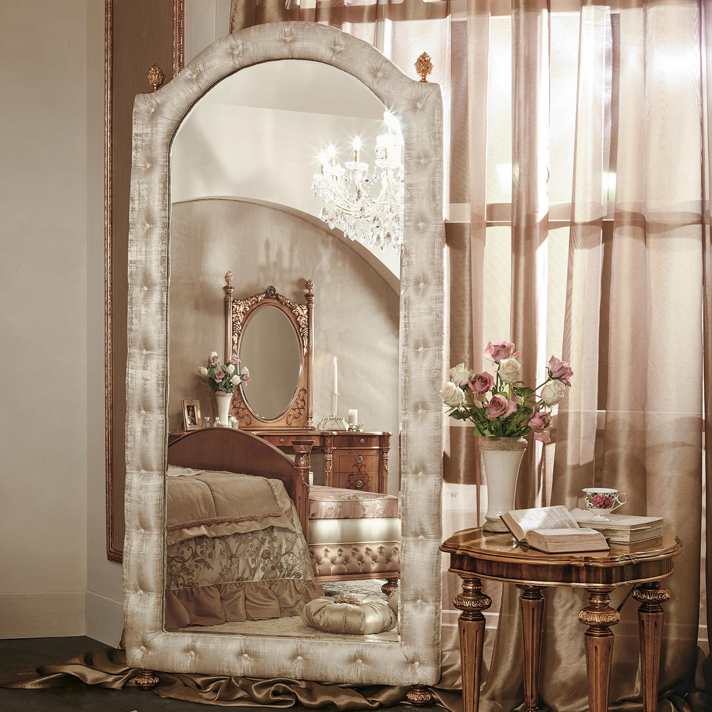 A rich and exclusive design characterizes this precious floor mirror, fancy addition to classic or eclectic decors. Crafted of wood, the rectangular frame has a curved top element and is upholstered in subtly shiny, beige-hued fabric enlivened by a