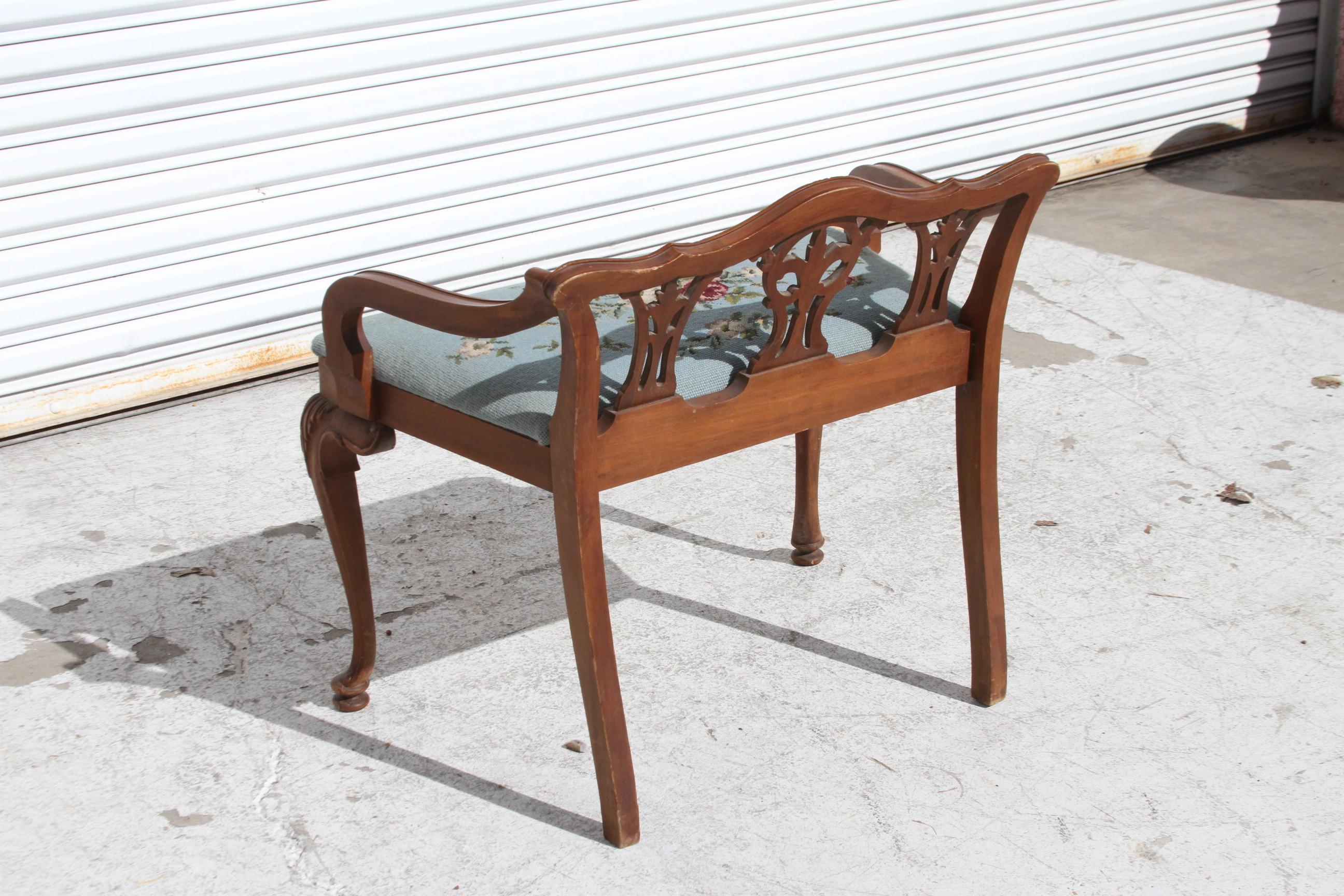 This is a beautiful French Style vanity stool. The short back has design. The arms are rolled. The feet are padded and it has a needlepoint fabric. A beautifully made piece of furniture.