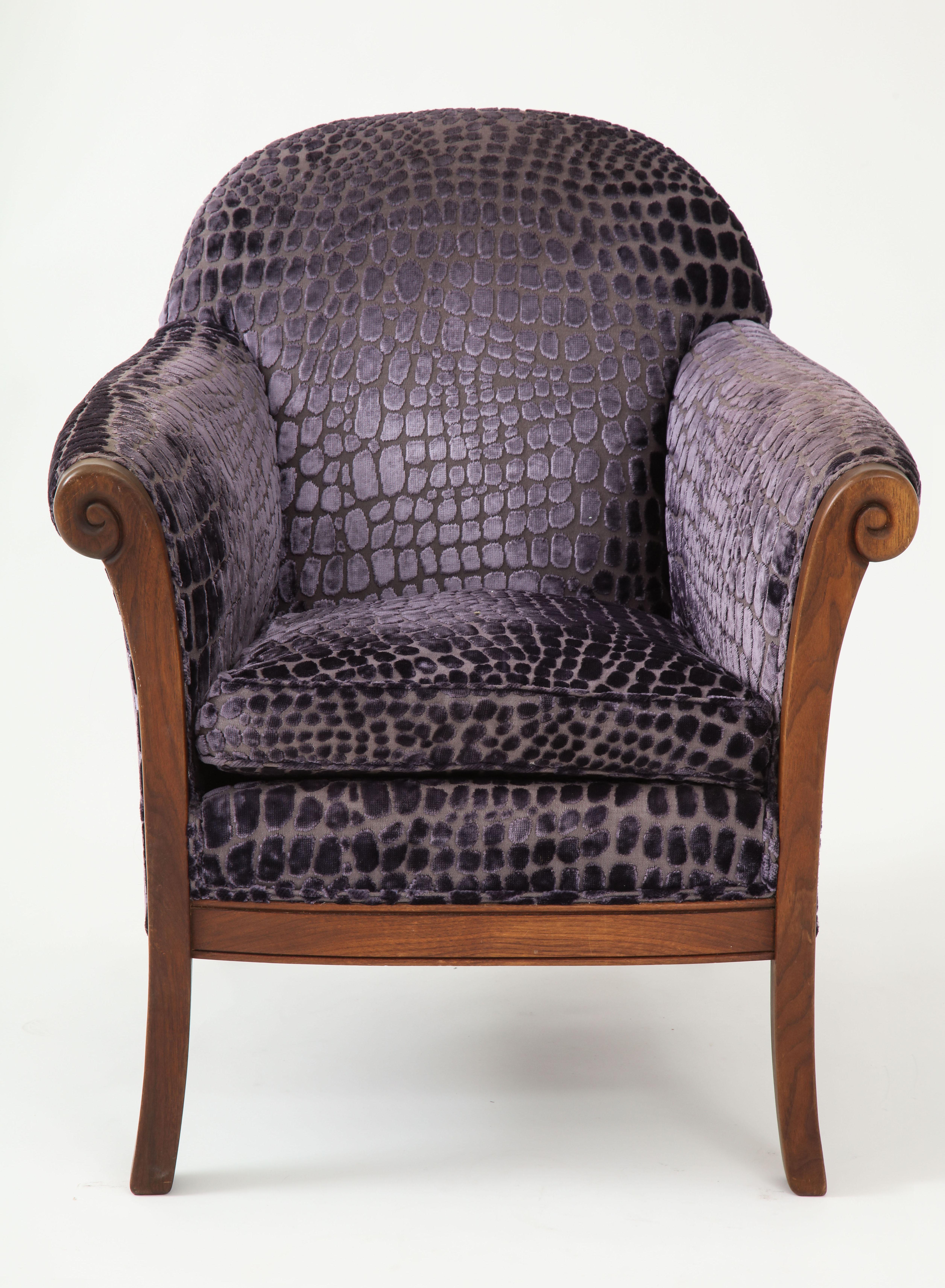 A pair of fine quality comfortable mid century chairs with hand carved mahogany frames and upholstered in a patterned snakeskin purple /grey velvet fabric.
