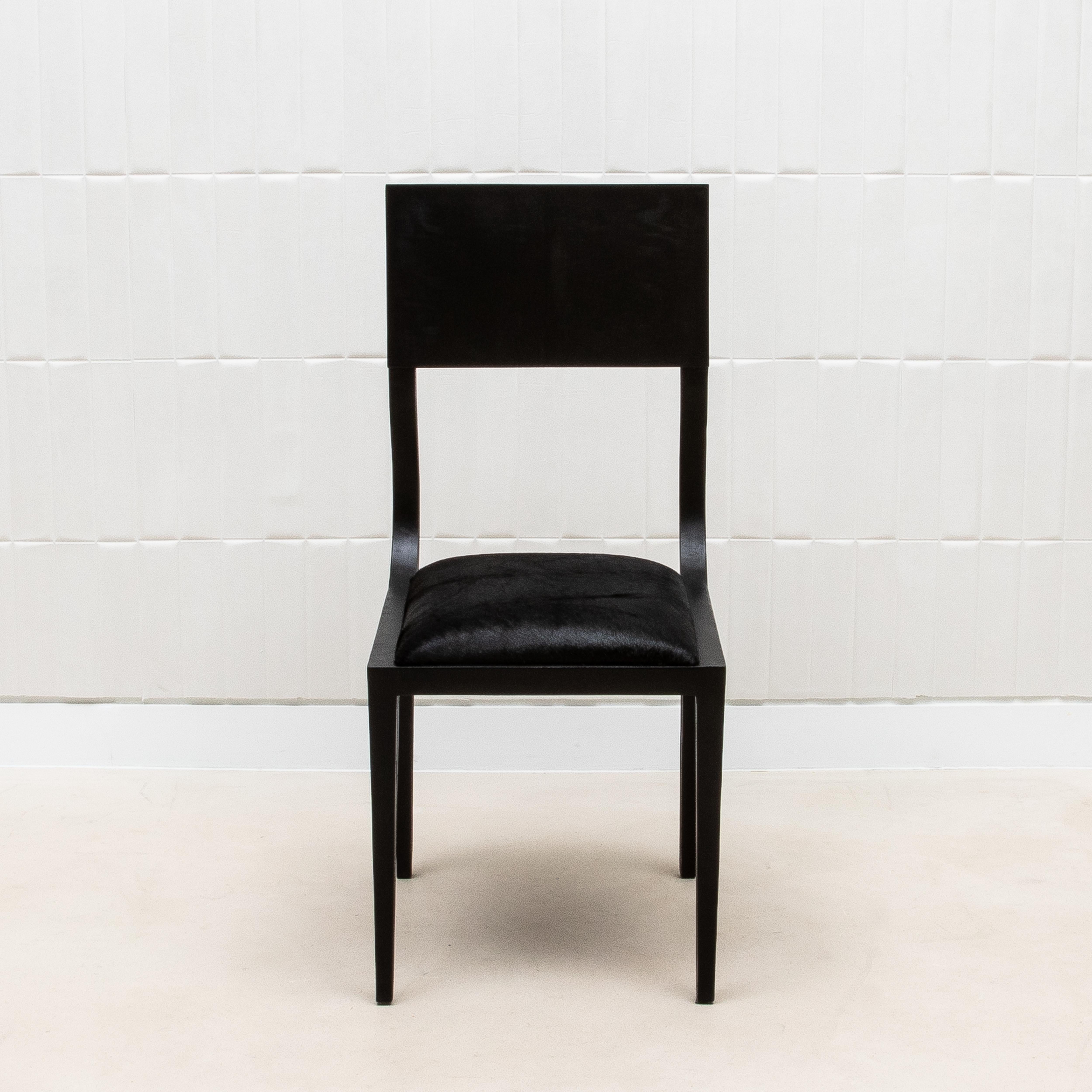 La sedia Lola di R&Y Augousti è una miscela sublime di artigianato e sobria opulenza, realizzata con la migliore quercia nera e rivestita in lussuosa e vellutata pelle di mucca nera. Questa sedia emana un'eleganza senza tempo, con le sue linee