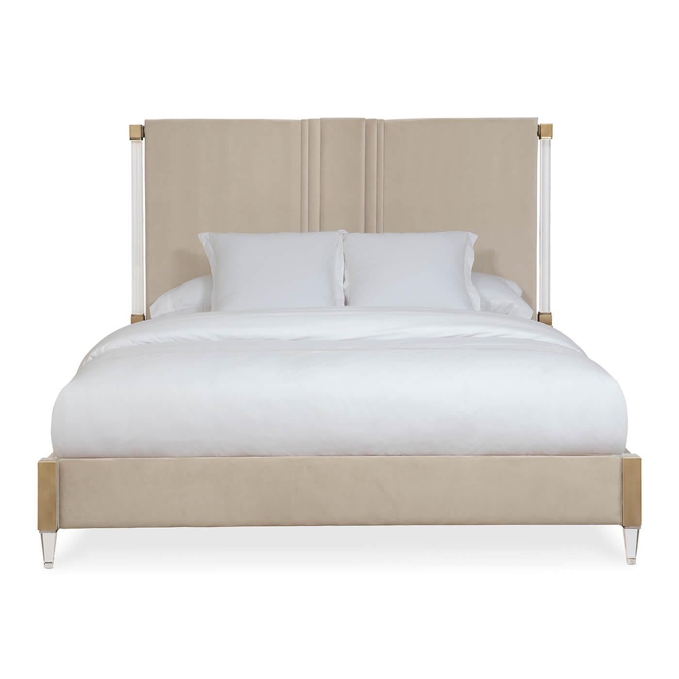 An upholstered king bed with lucite and bronze accents. This beautiful bed is upholstered with luxury fabric in the softest shade of sand. The base of the headboard and footboard are detailed with smoked bronze accents. The head posts and front feet