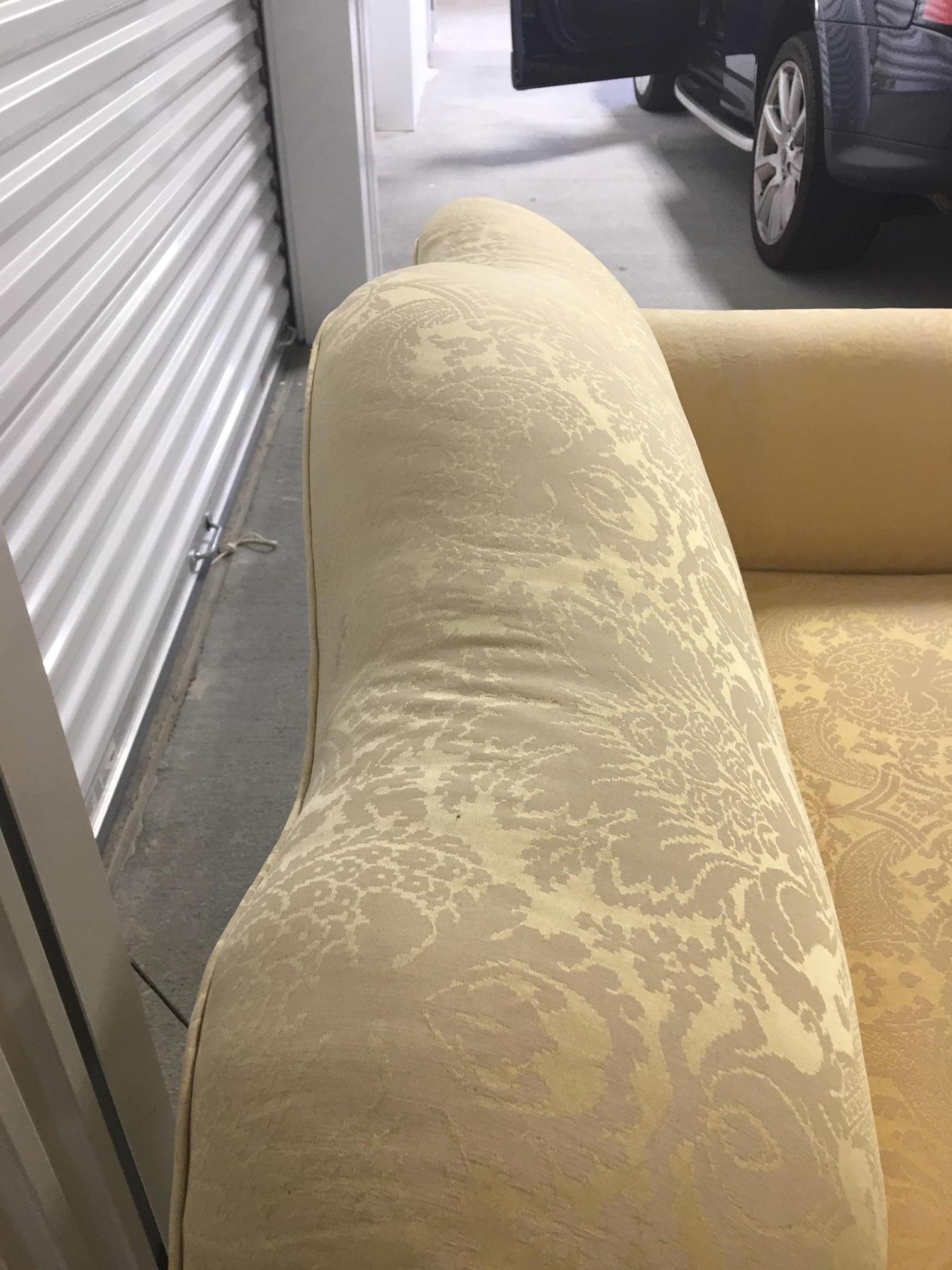 Upholstered loveseat in a yellow damask fabric, 20th century.
