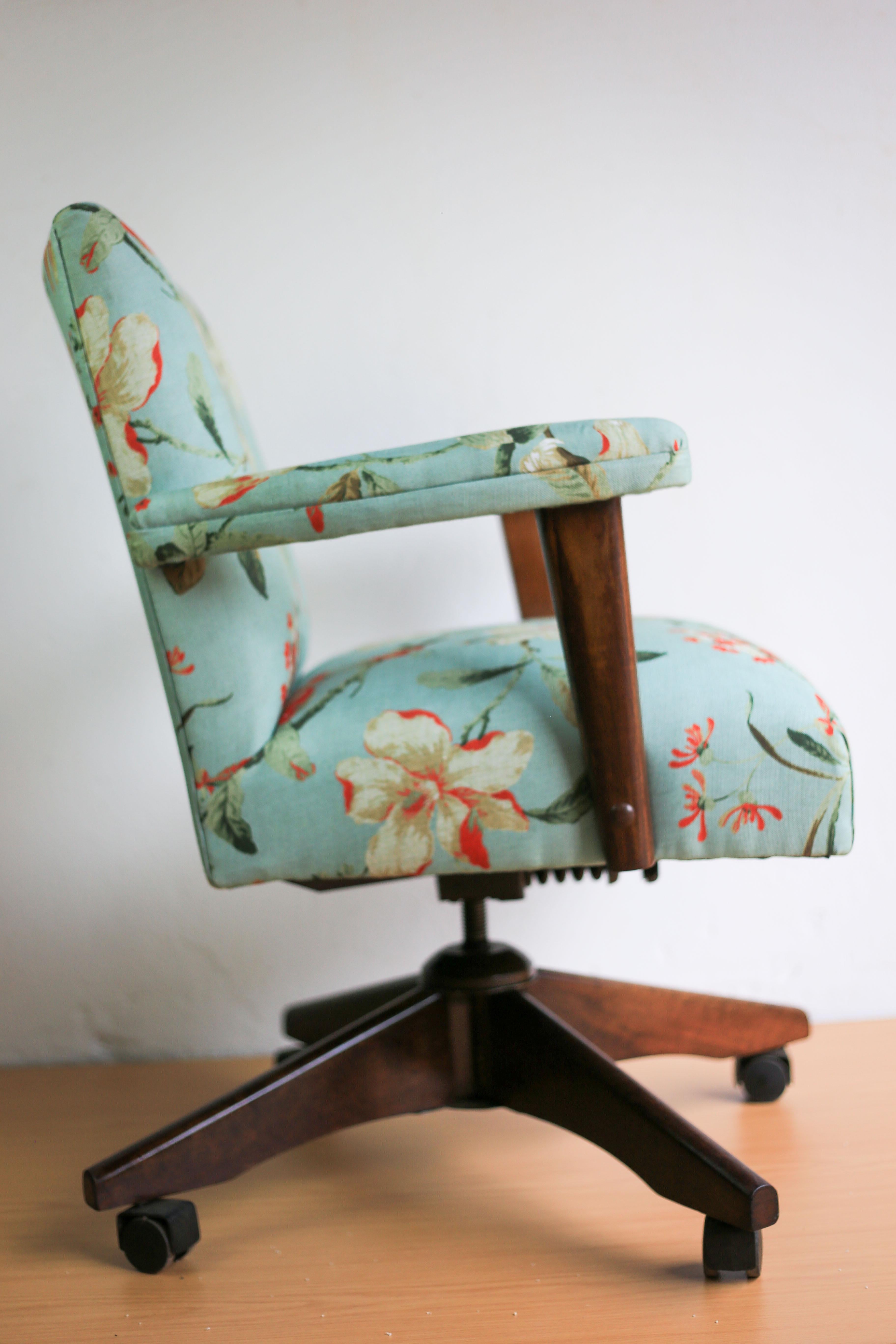 A very comfortable, early 20th century office chair with a strong wood base and arms. It is recovered in a floral linen type fabric by UK fabric design house, Laura Ashley. The chair can swivel, tilt and is height adjustable. It moves freely on four