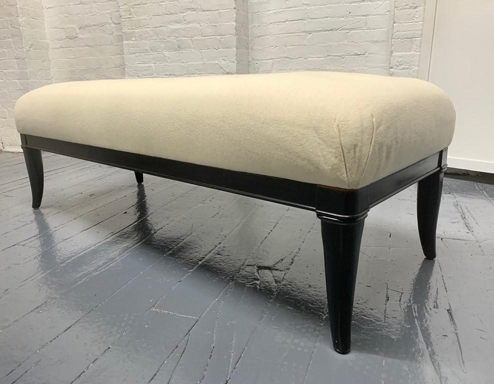Upholstered tufted bench style of Robsjohn-Gibbings. Black lacquered wood legs with a newly upholstered linen-blend fabric.