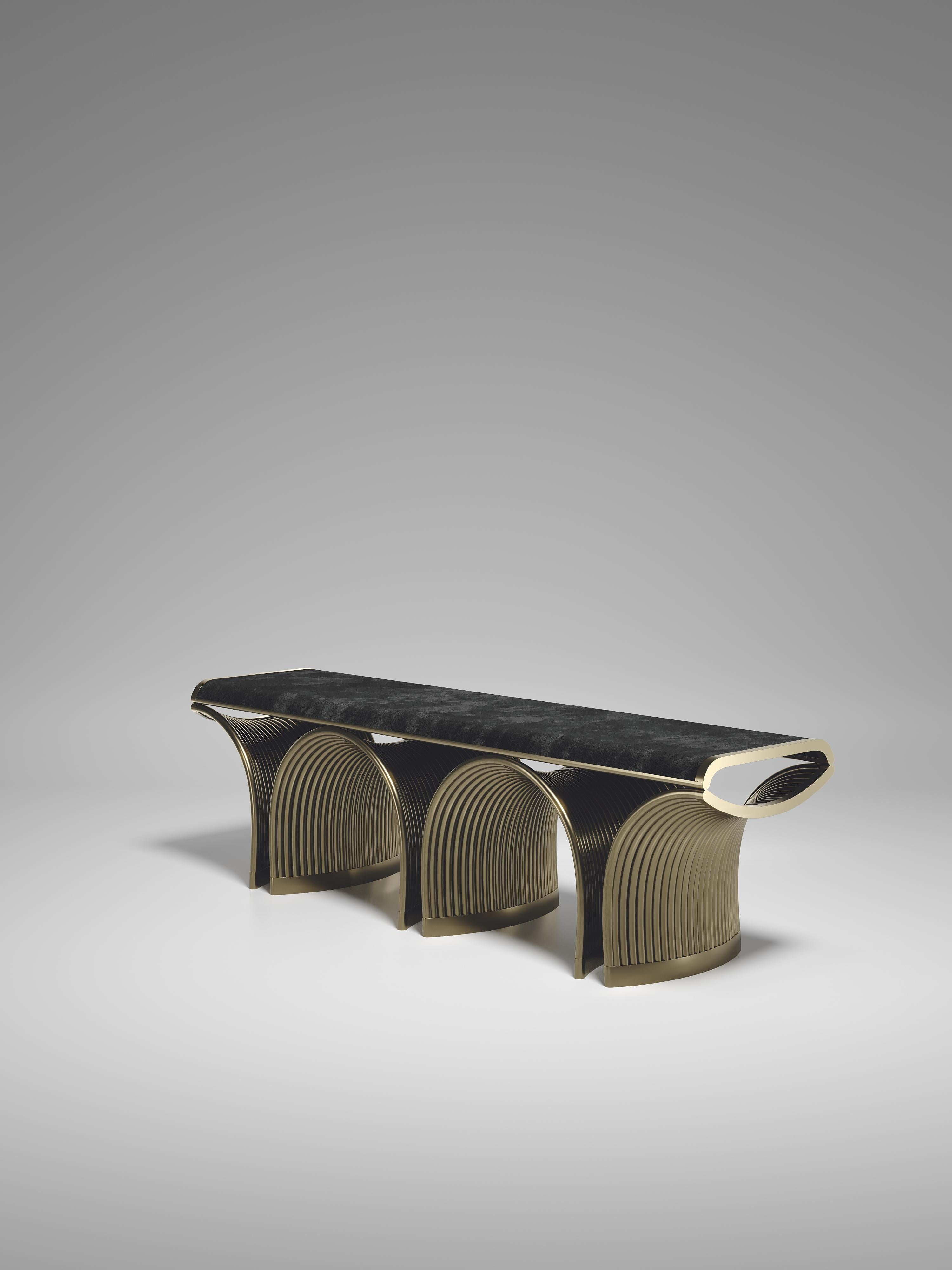 The Nymphea bench by R&Y Augousti upholstered in dark grey velvet with bronze-patina brass details explores the brand's iconic DNA of bringing old world artisanal craft into a contemporary and utterly luxury feel. The base of the bench is