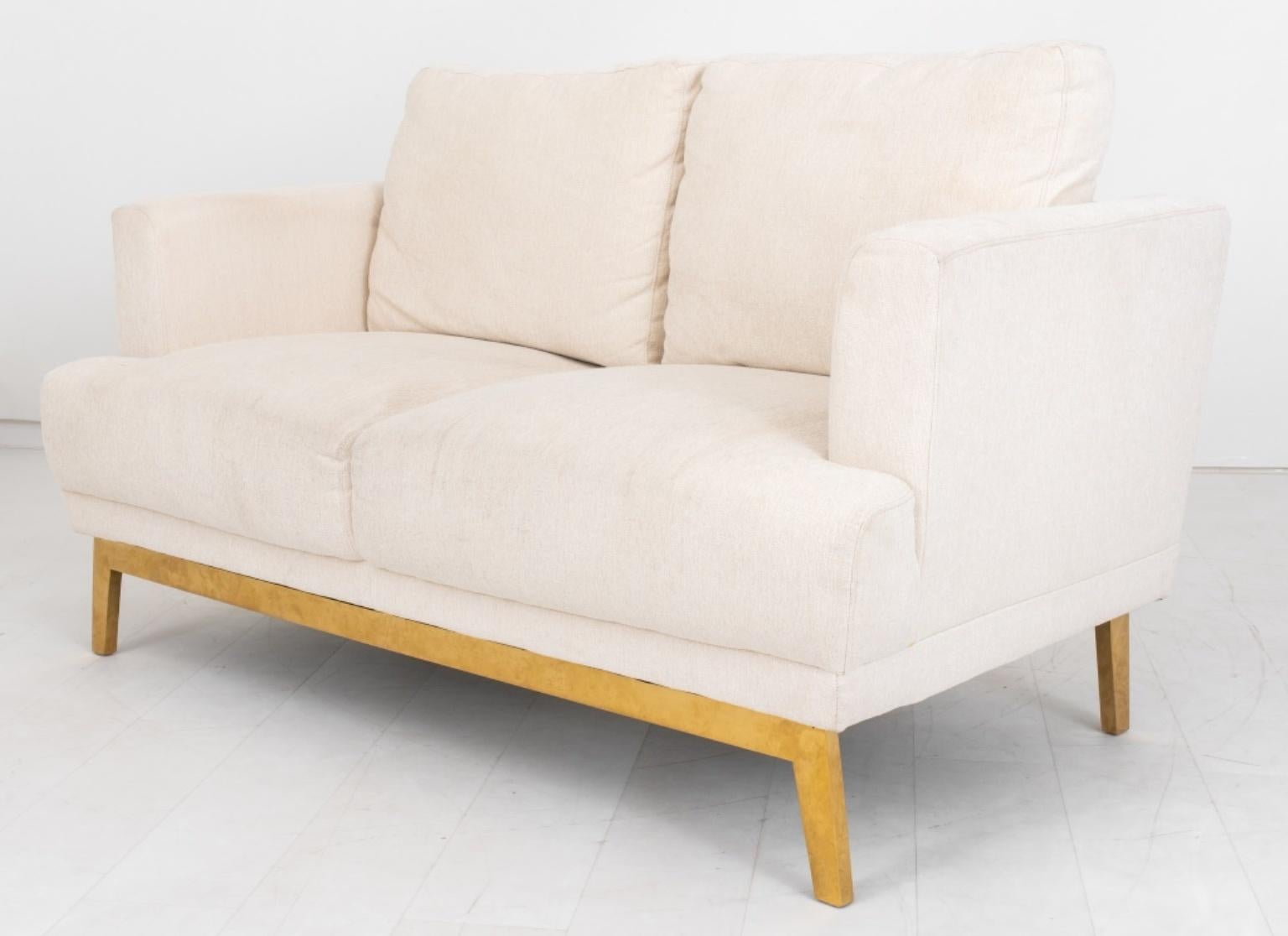 Upholstered white Haitian cotton upholstered two seat sofa on Brass base, with square back and seat between upholstered arms, and four drop in cushions above a brass base with splay feet,. 

Dimensions: 35