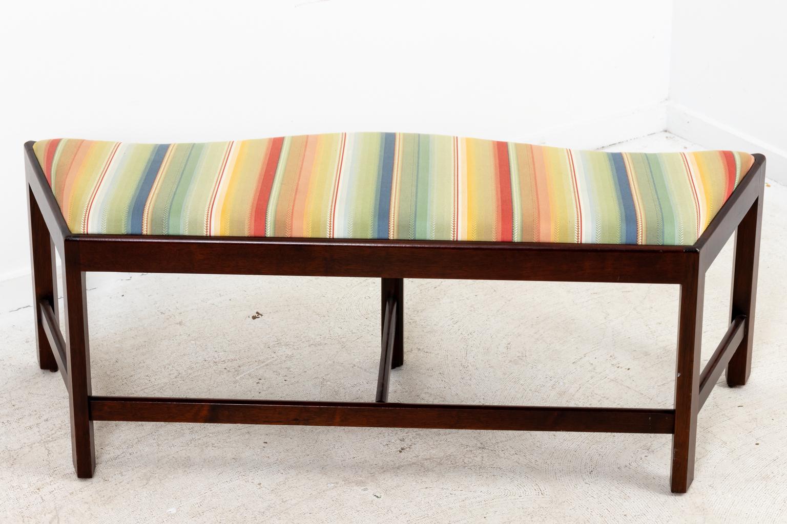 Circa 1970-1980s upholstered window bench in the Mid-Century Modern style with angled sides, curved front, and bottom stretcher. The piece features clean striped upholstery and measures 48.00 Inches across the front and 36.50 Inches across the back