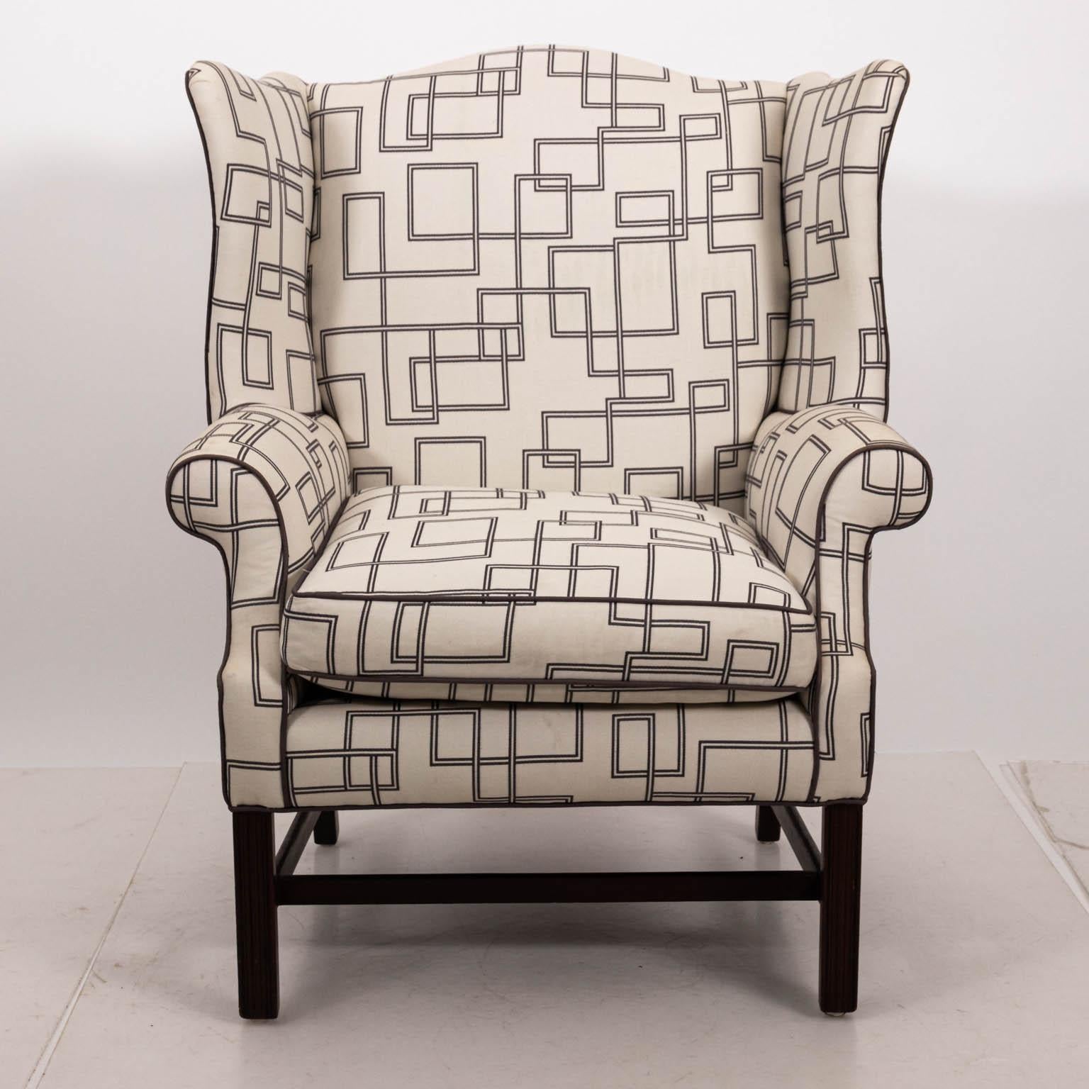 Wide wingback armchair with square wood legs and bottom stretchers, circa 21st century. The piece is also upholstered in contemporary white cotton fabric featuring geometric navy color motifs. Please note of wear consistent with age including small