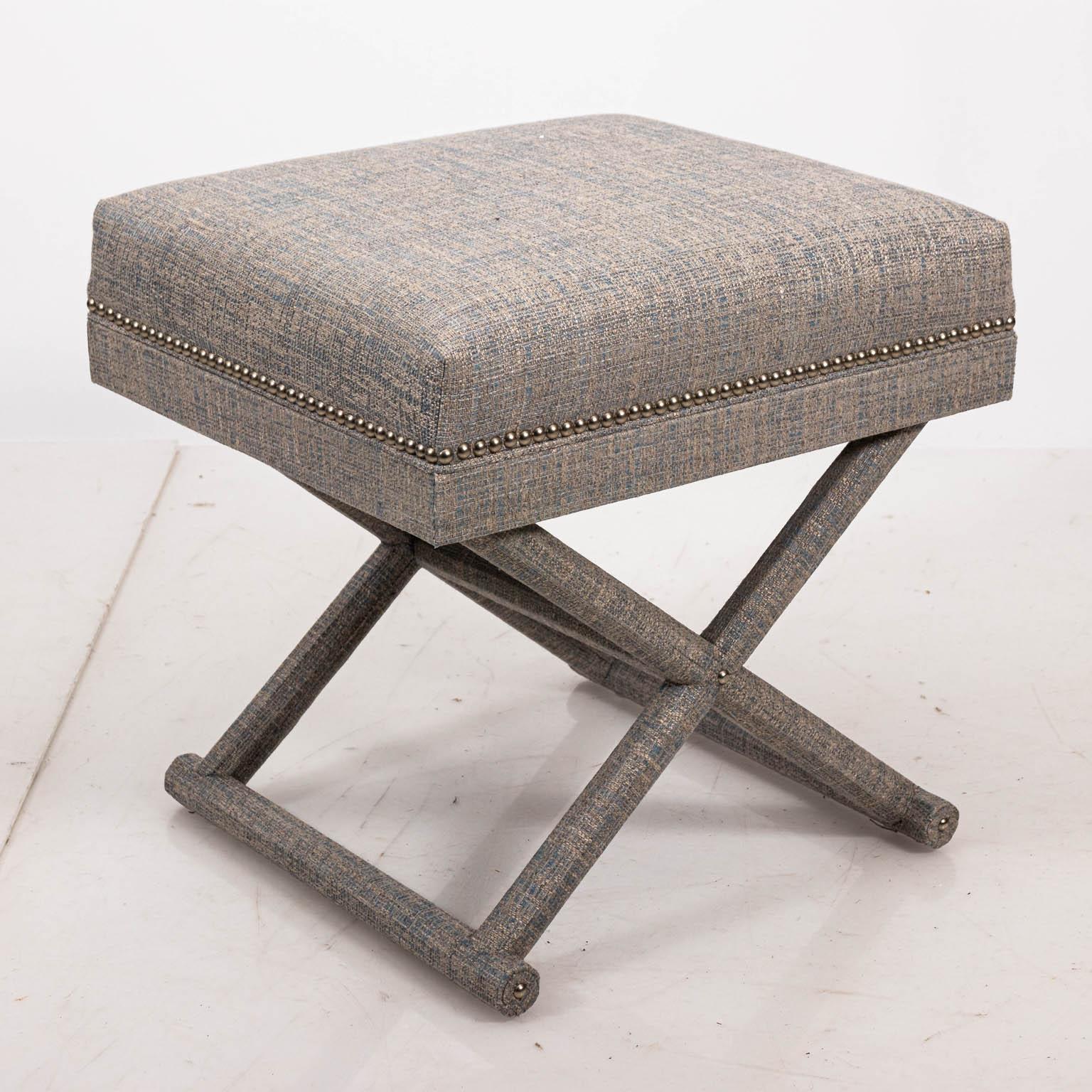 Upholstered X-frame bench with fabric cushion and metal nail head trim. Please note of wear consistent with age.
