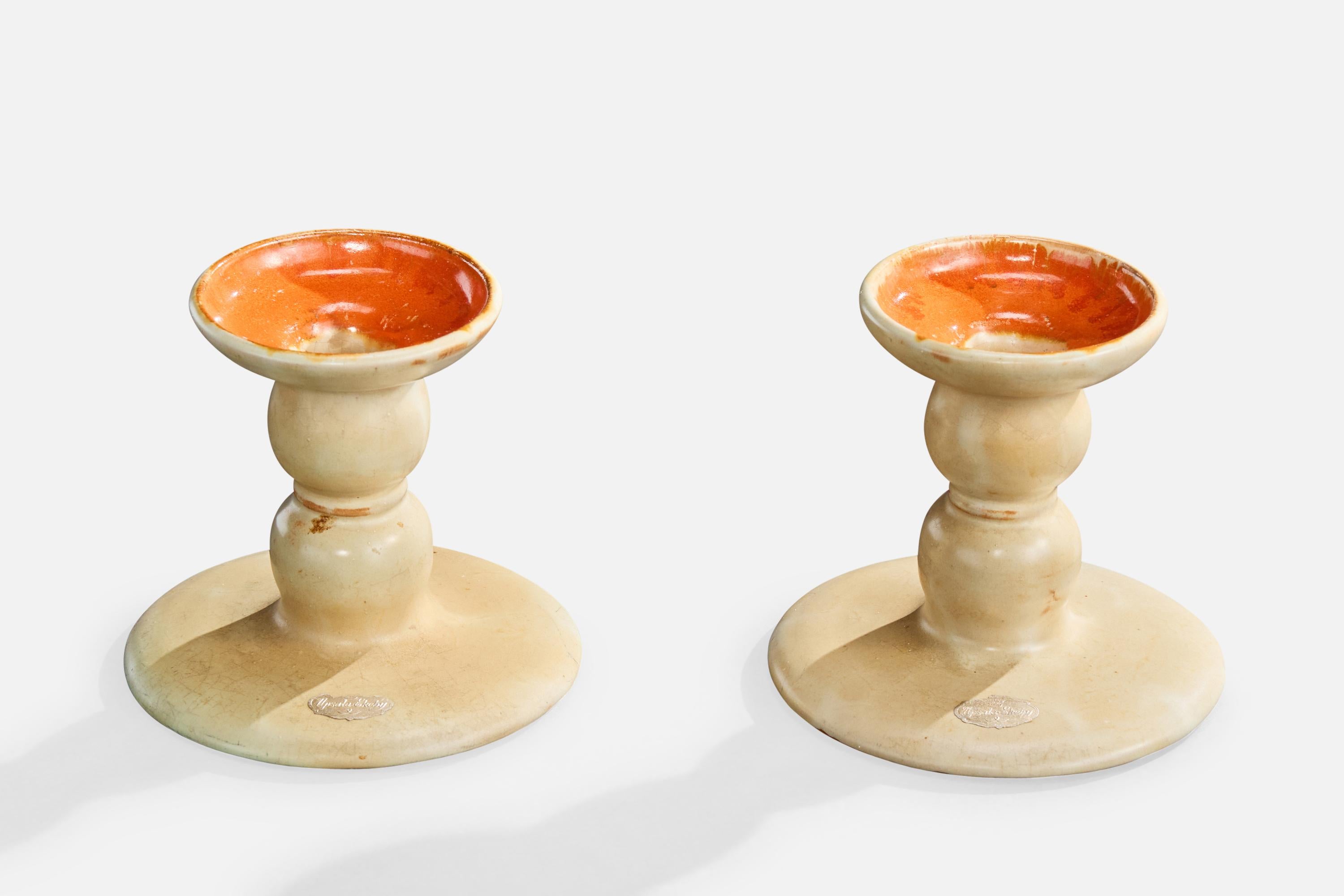 A pair of cream-white and orange-glazed ceramic candlesticks produced by Upsala Ekeby, Sweden, c. 1930s.

Overall Dimensions (inches): 4