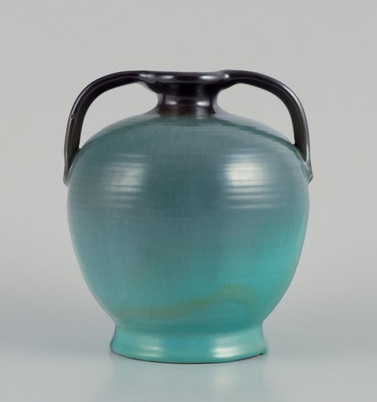 Vase en céramique Upsala Ekeby avec deux poignées 
Glaçure dans les tons verdâtres.
Modèle 1559.
Suède. ca. 1940.
Marqué.
En parfait état.
Dimensions : Hauteur 15,0 cm x Diamètre 12,0 cm : Hauteur 15,0 cm x Diamètre 12,0 cm.