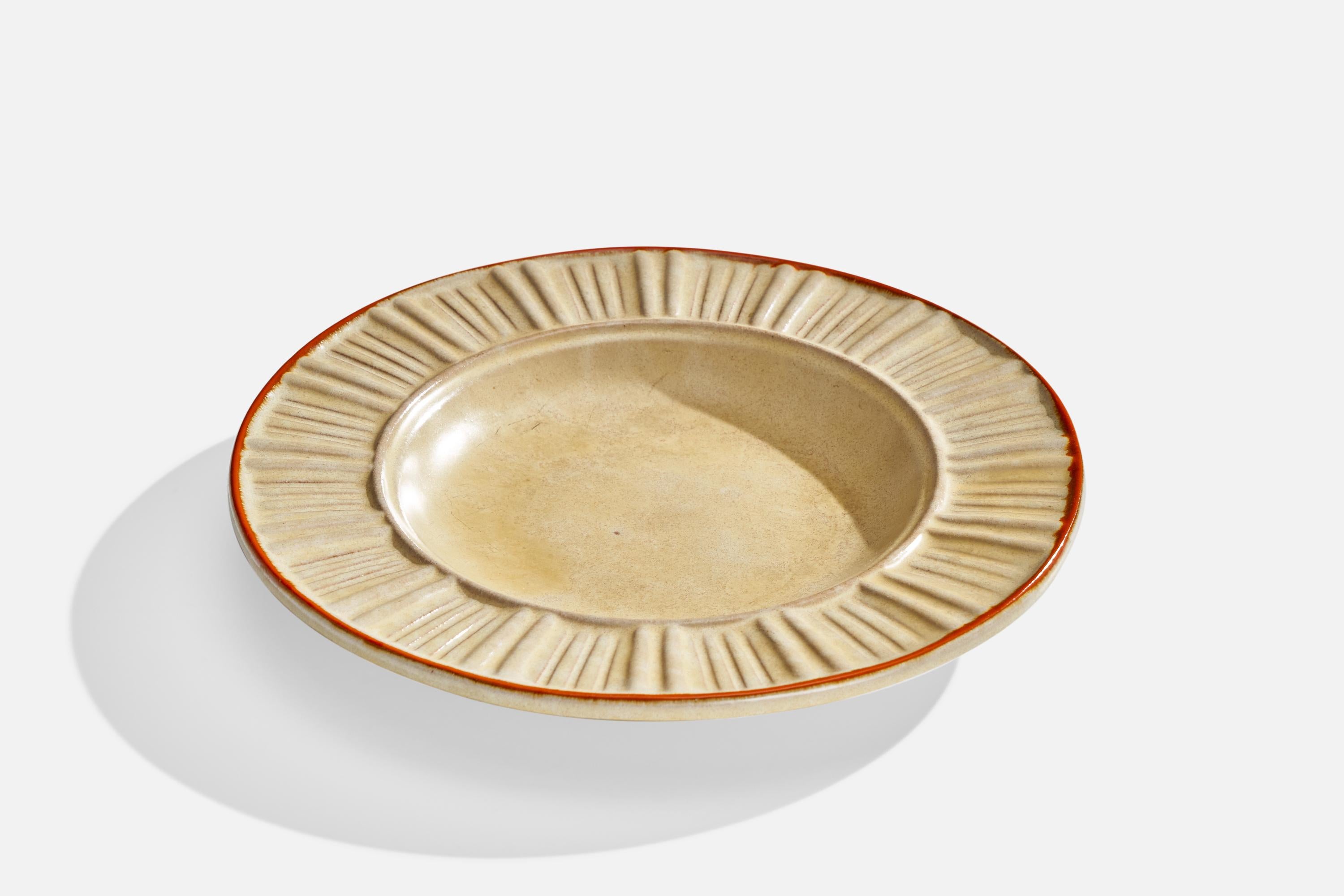 A beige and orange-glazed earthenware dish designed and produced by Upsala Ekeby, Sweden, 1930s.