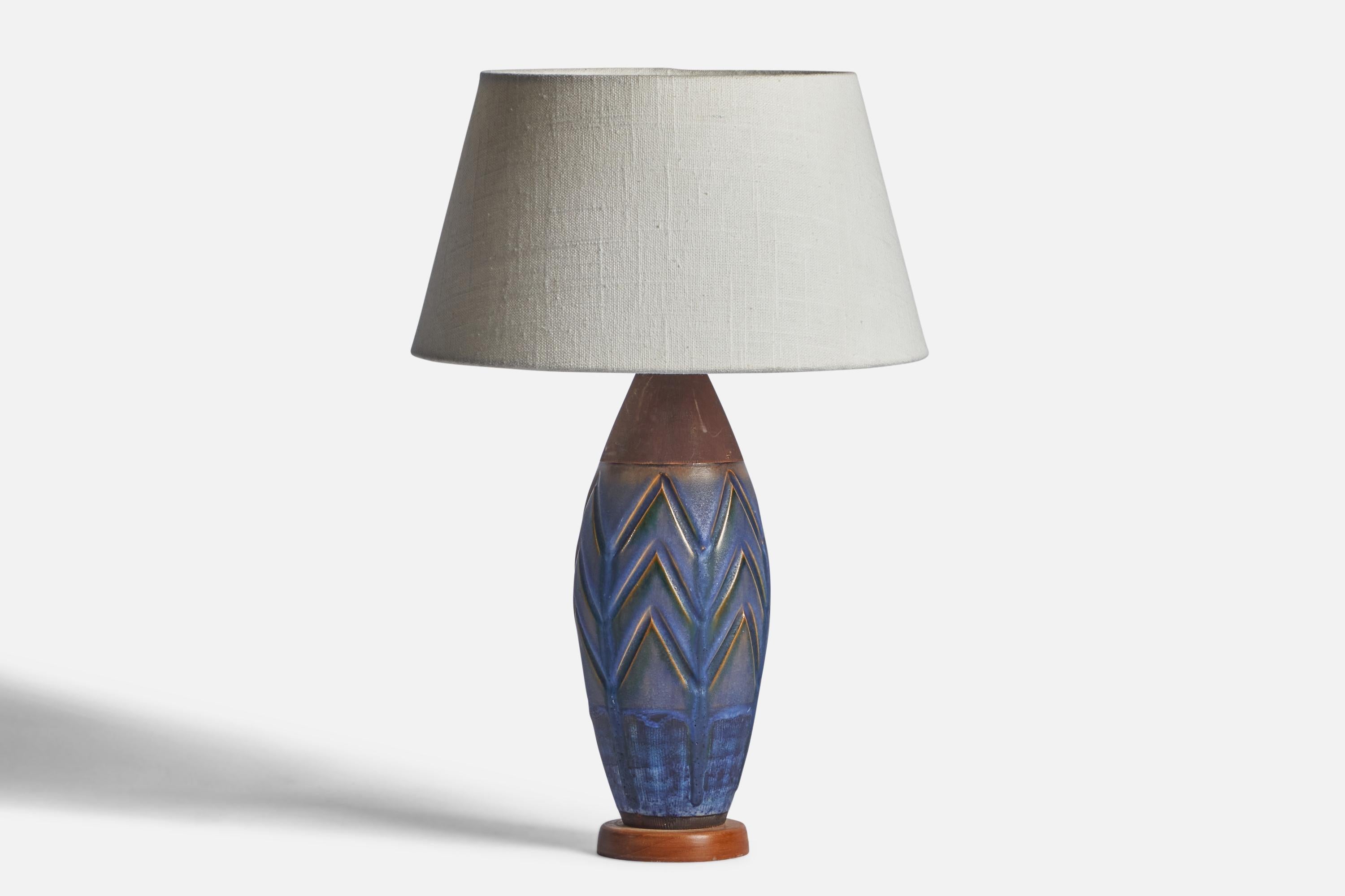 A blue and brown-glazed ceramic and wood table lamp designed and produced by Upsala Ekeby, Sweden, 1950s.

Dimensions of Lamp (inches): 12.35” H x 3.9” Diameter
Dimensions of Shade (inches): 7” Top Diameter x 10” Bottom Diameter x 5.5” H 
Dimensions