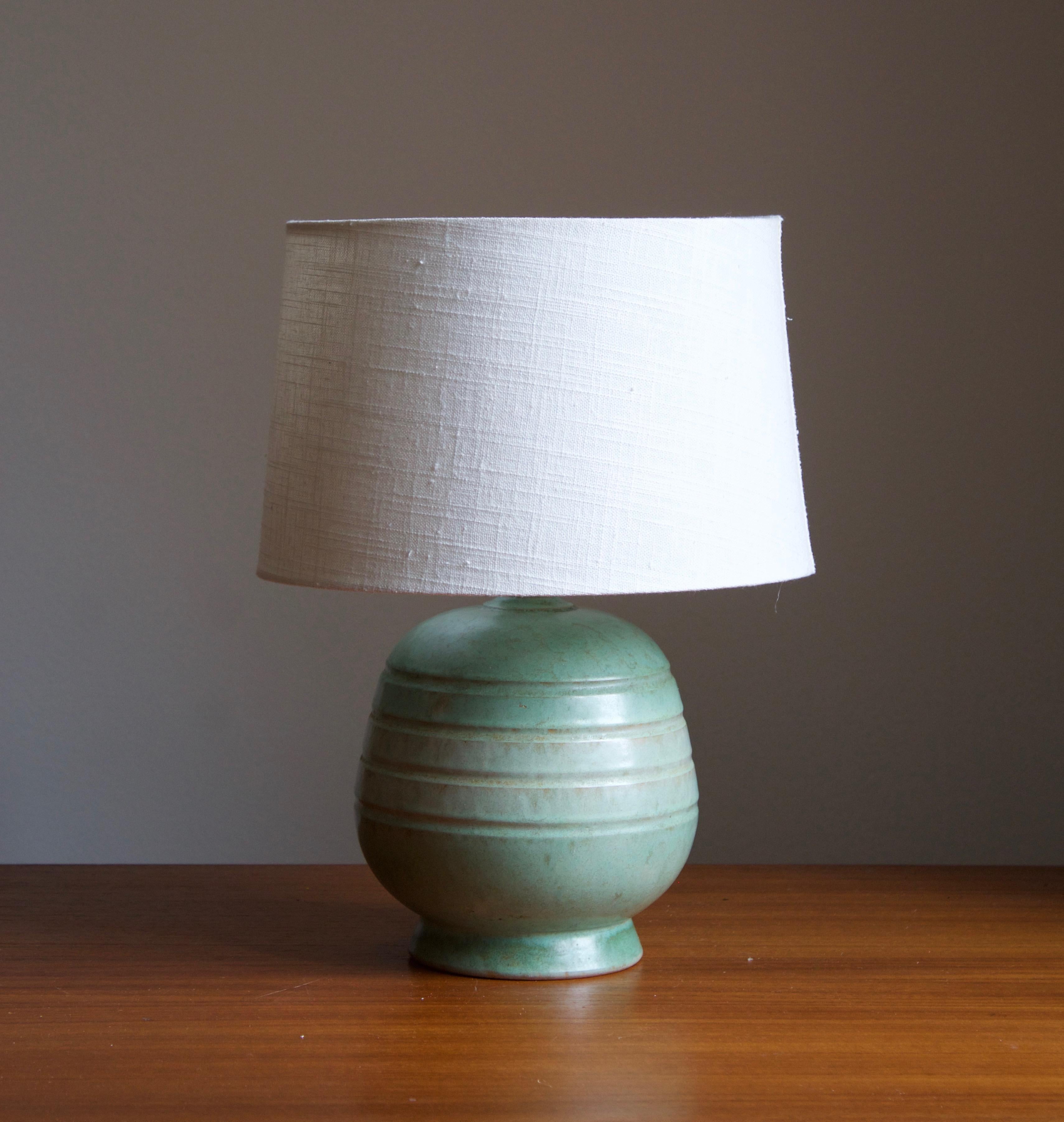 An early modernist table lamp. Production attributed to Upsala-Ekeby, Sweden, 1930s.

Stated dimensions exclude lampshade. Height includes the socket. Sold without lampshade.

Glaze features a green color with hints of brown.

Other designers of the