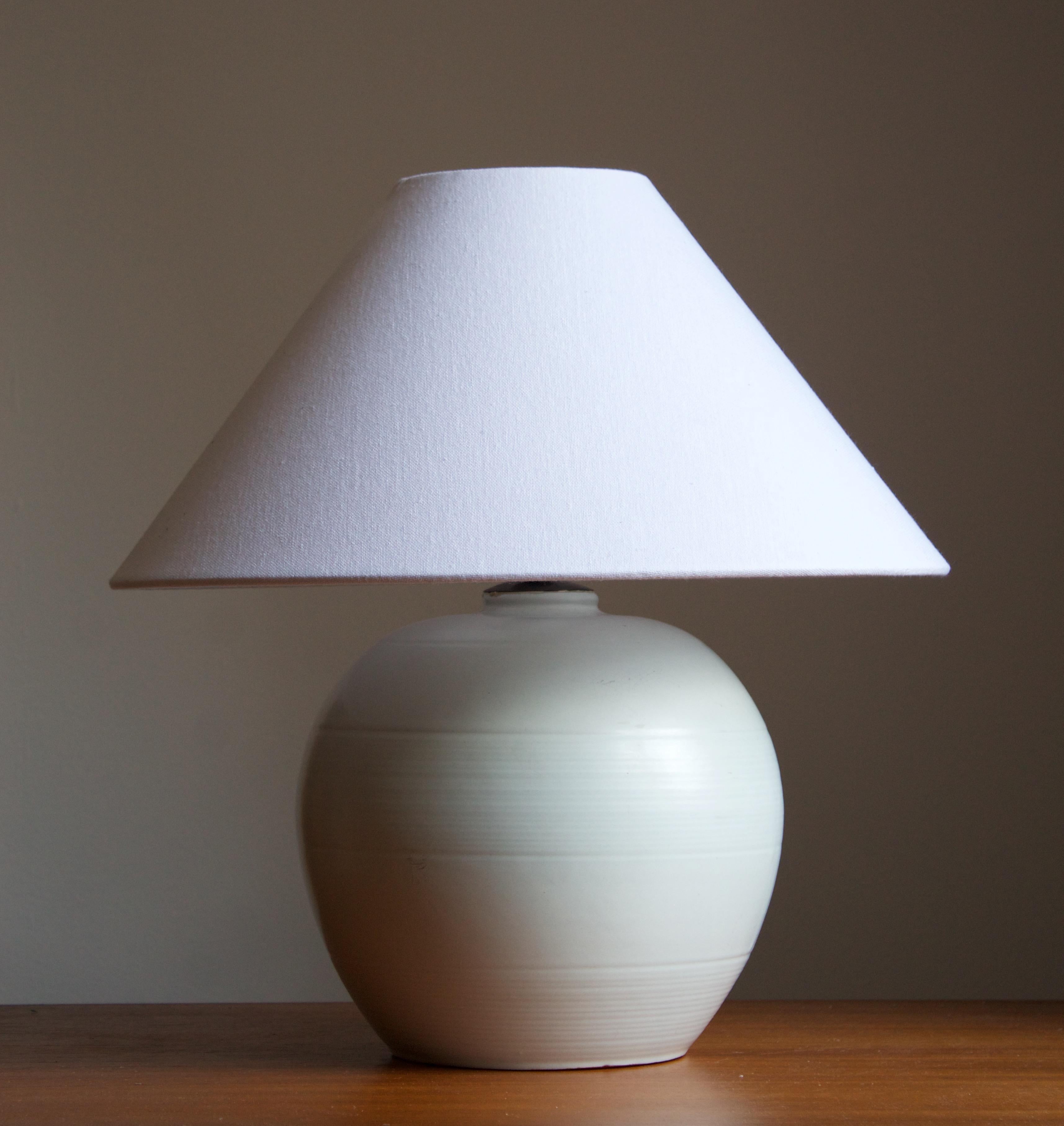 An early modernist table lamp. by Upsala-Ekeby, Sweden, 1930s. Stamped. Incised decor. 

Stated dimensions exclude lampshade. Height includes the socket. Sold without lampshade.

Glaze features a white-grey color.

Other designers of the period