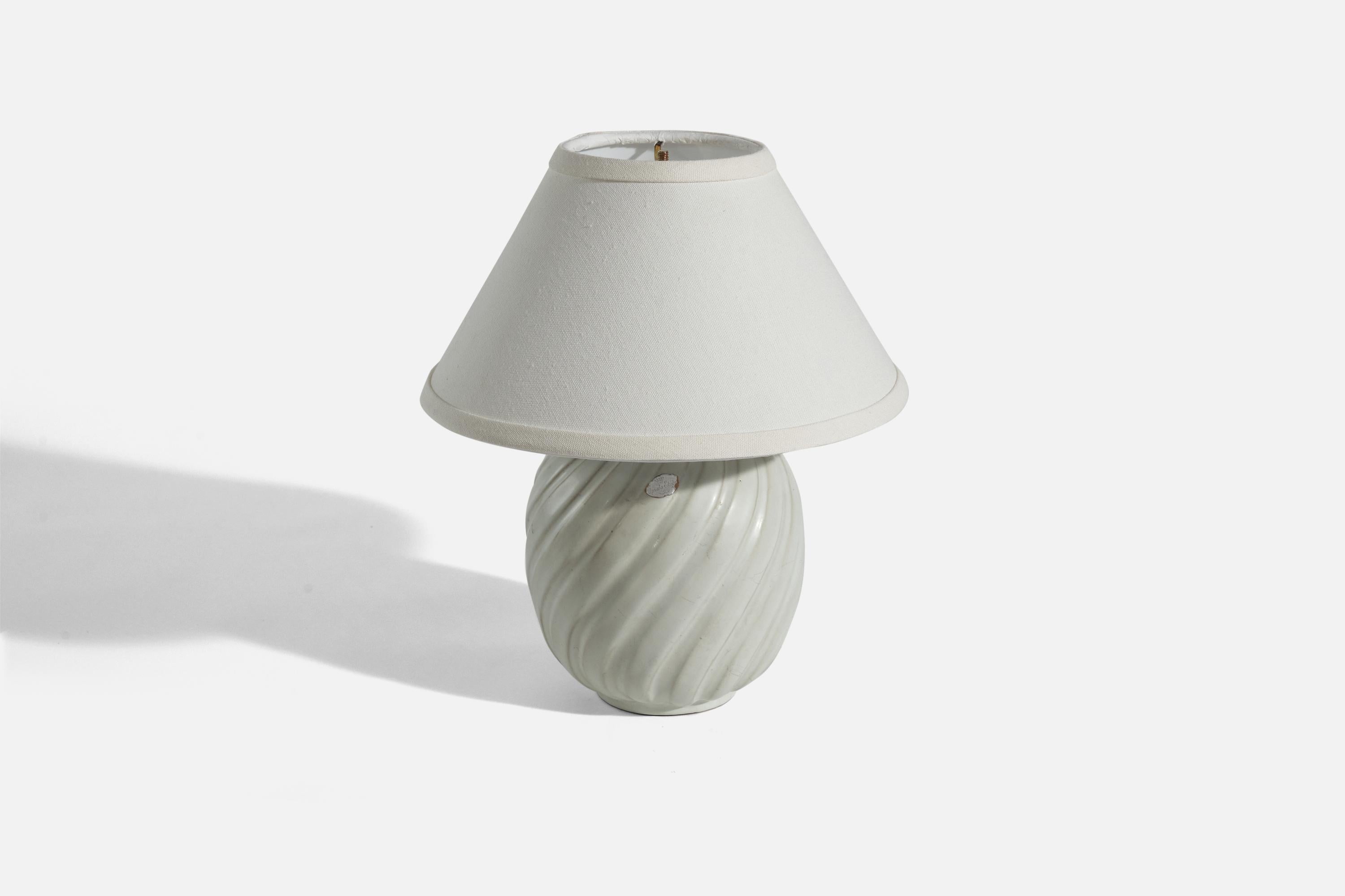 A white, glazed earthenware and brass table lamp designed and produced by Upsala-Ekeby, Sweden, 1940s.

Sold without lampshade. 
Dimensions of lamp (inches) : 10.18 x 6 x 6 (height x width x depth)
Dimensions of shade (inches) : 4.25 x 10.25 x 6