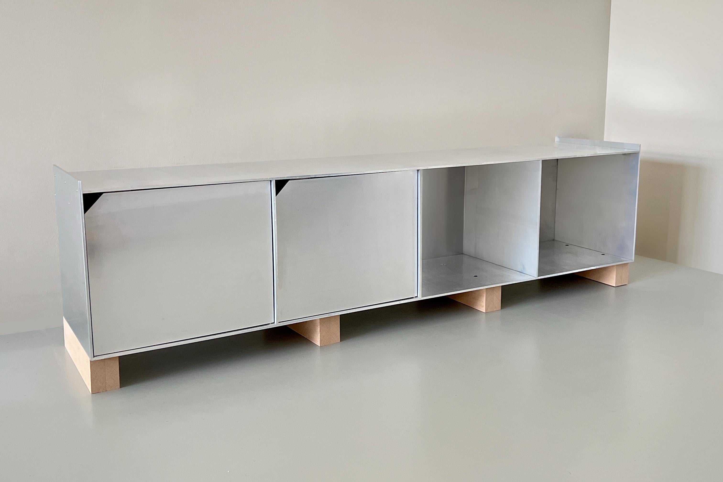 'Upton' Low Sideboard is a beautifully simplistic piece that shows the aluminium in its raw form, with contrasting beech legs.

The sheets of aluminium plate are left machine milled and are mechanically fixed together using countersunk bolts.

The
