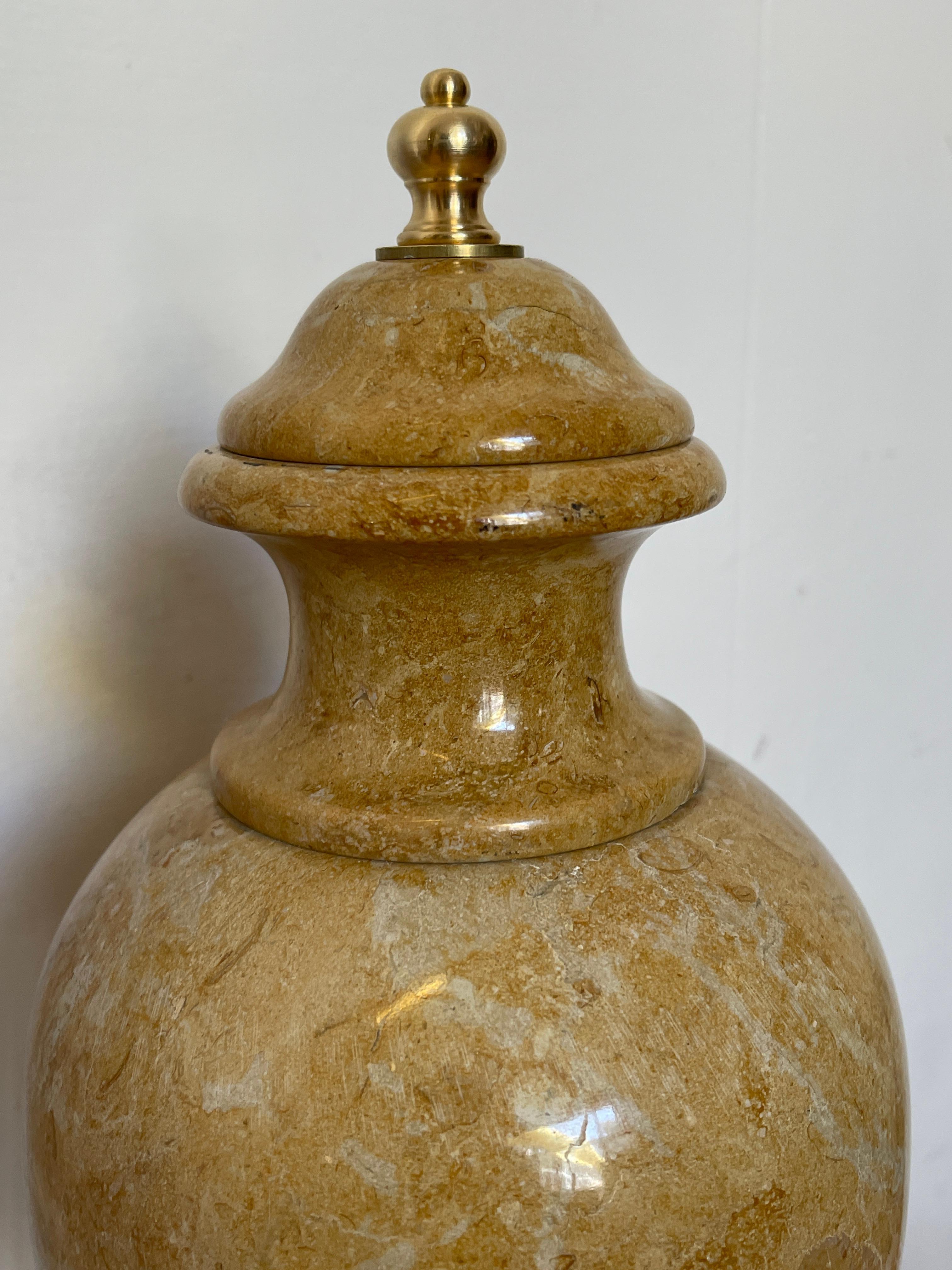 Une urne décorative raffinée en précieux marbre Giallo Siena, avec une finition polie caractéristique qui met en valeur les veines naturelles de la pierre. Le couvercle bombé avec bouton en laiton doré ajoute une touche classique et luxueuse. Montée