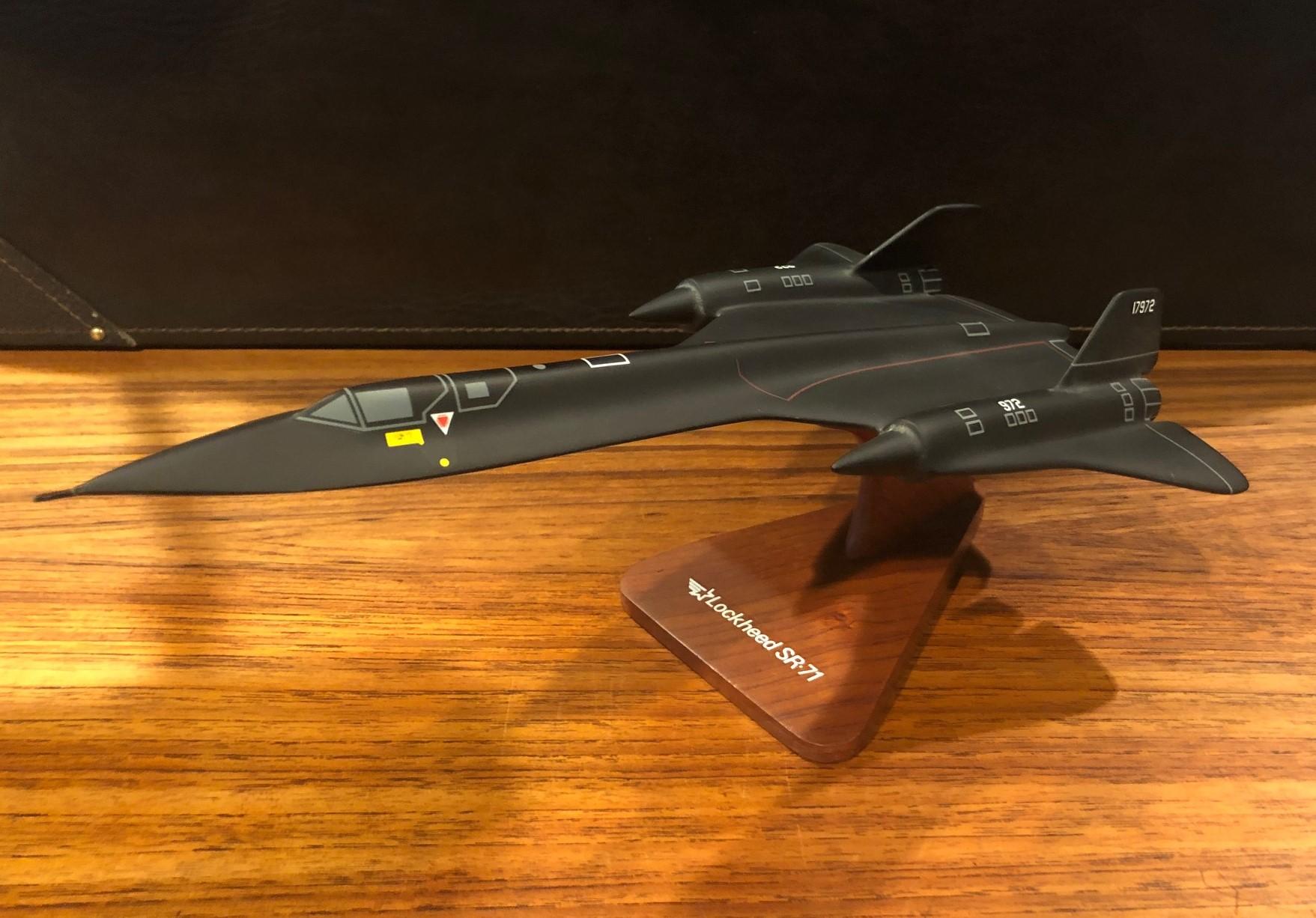 A very cool U.S. Air Force Lockheed SR-71 Blackbird airplane / jet desk model, circa 2000s. The piece is in very good condition and is made of a composite material and mounted on a triangular wood base; The plane has a great matte black finish and