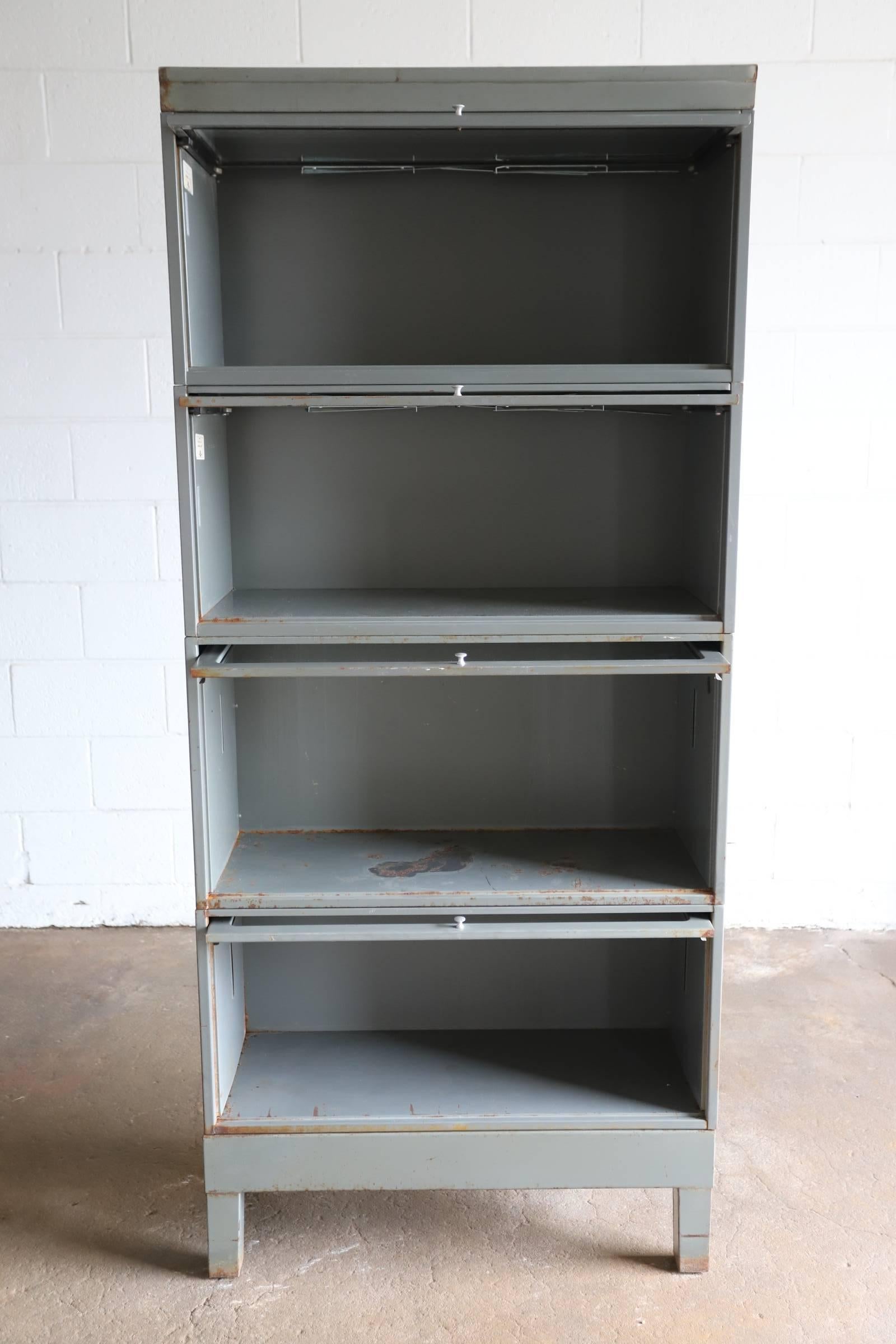Industrial metal stacking lawyer or barrister bookcase with glass doors. Original gunmetal gray. Consists of six pieces, a base, a top and four boxes with glass doors. Boxes can be arranged in any order. From the collection Space 20th Century Modern.