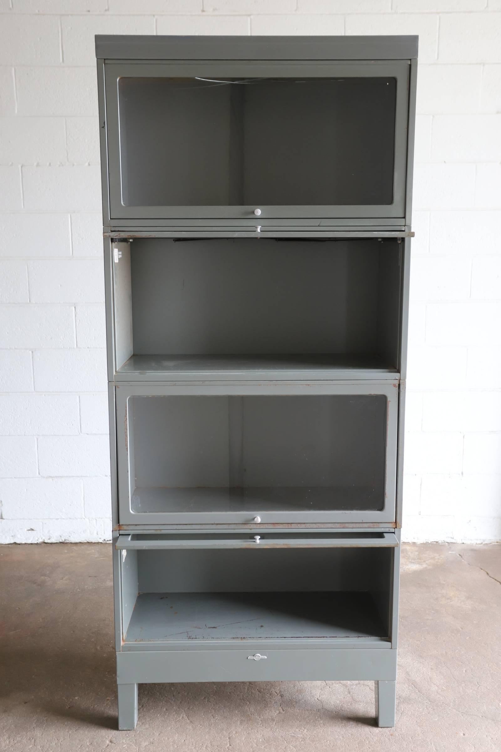 Industrial metal stacking lawyer or barrister bookcase with glass doors. Original gunmetal grey. Consists of six pieces, a base, a top and four boxes with glass doors. Boxes can be arranged in any order.