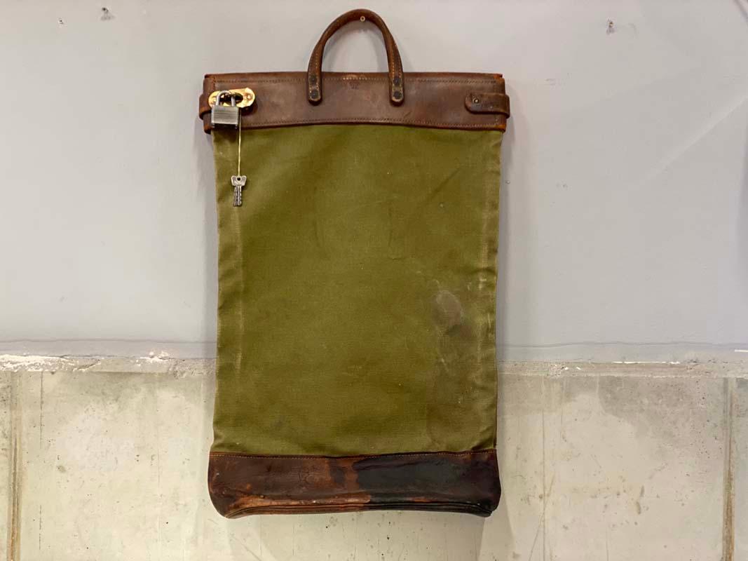Original US-American railroad mailbag from the 1920s-1930s. The handle and straps are made of leather, the strap is led through metal loops so that the bag can be closed with a padlock. The linen part of the bag has the inscription 