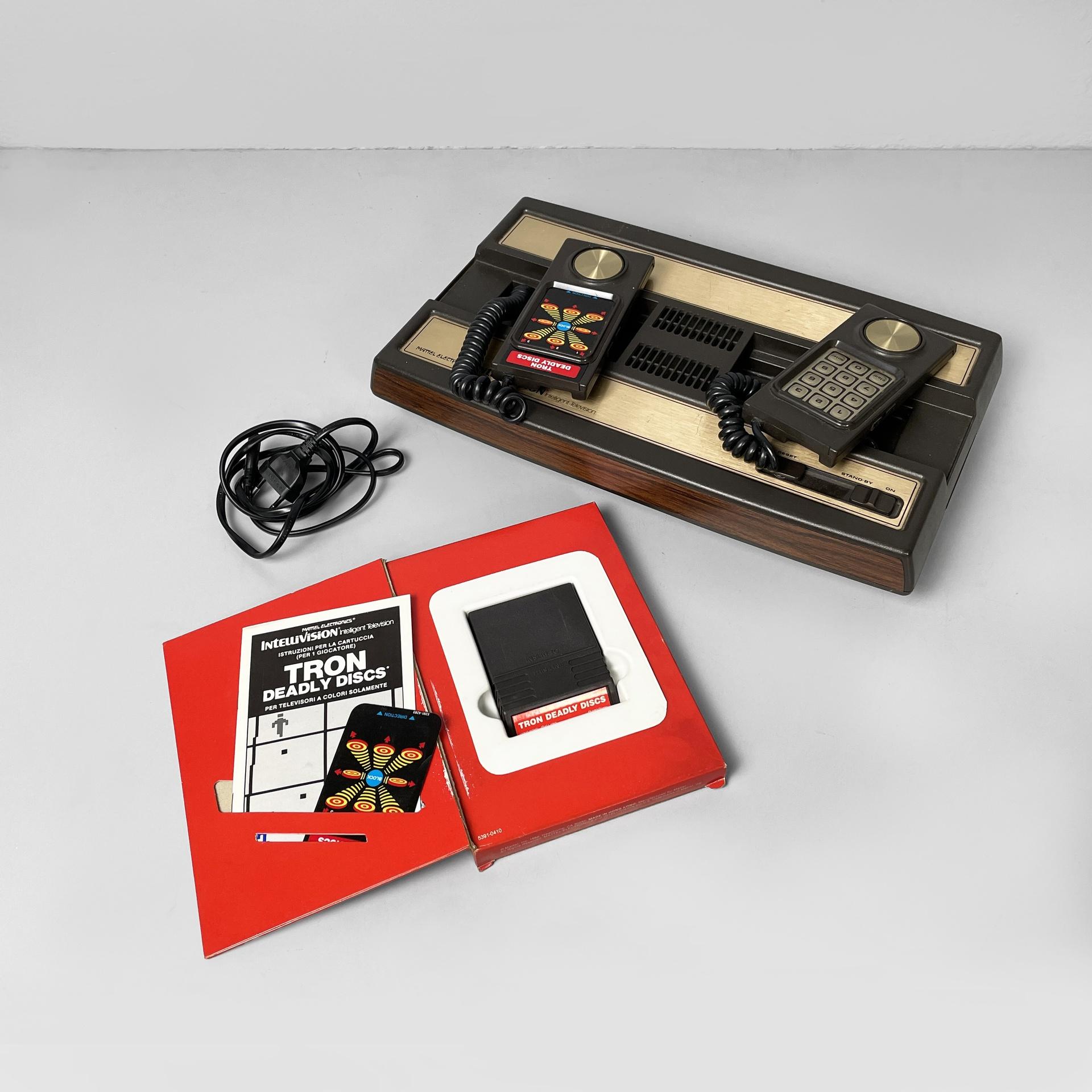 Usa console Intellivision and Tron deadly discs videogame by Mattel, 1980s
Console model Intellivision and Tron Deadly Discs video game with original box. The rectangular console features two controllers, connected by a cable. Cable ports are