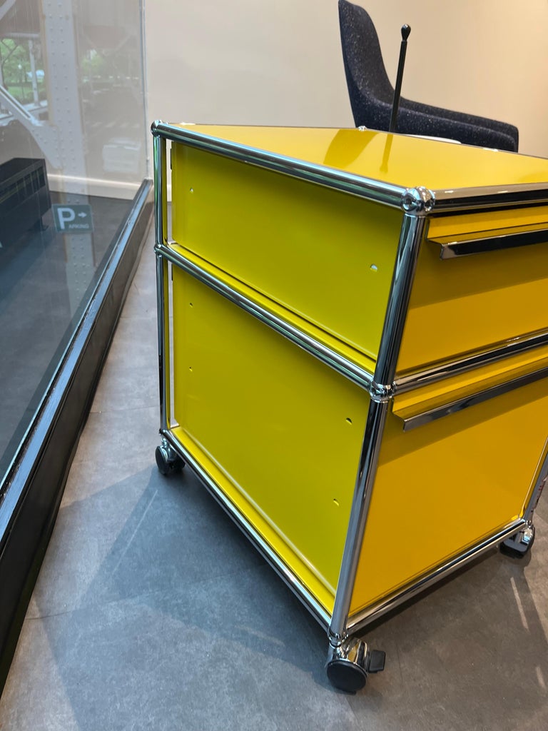 Offered by M2L. 
It has top drawer inserts 
LxDxH: 523x418x605 mm
Material: metal
Colour: golden yellow
2x open compartment
2x compartment incl. drawer with handle (without lock)
incl. castor, soft
 With one drop down door. Designed by Swiss
