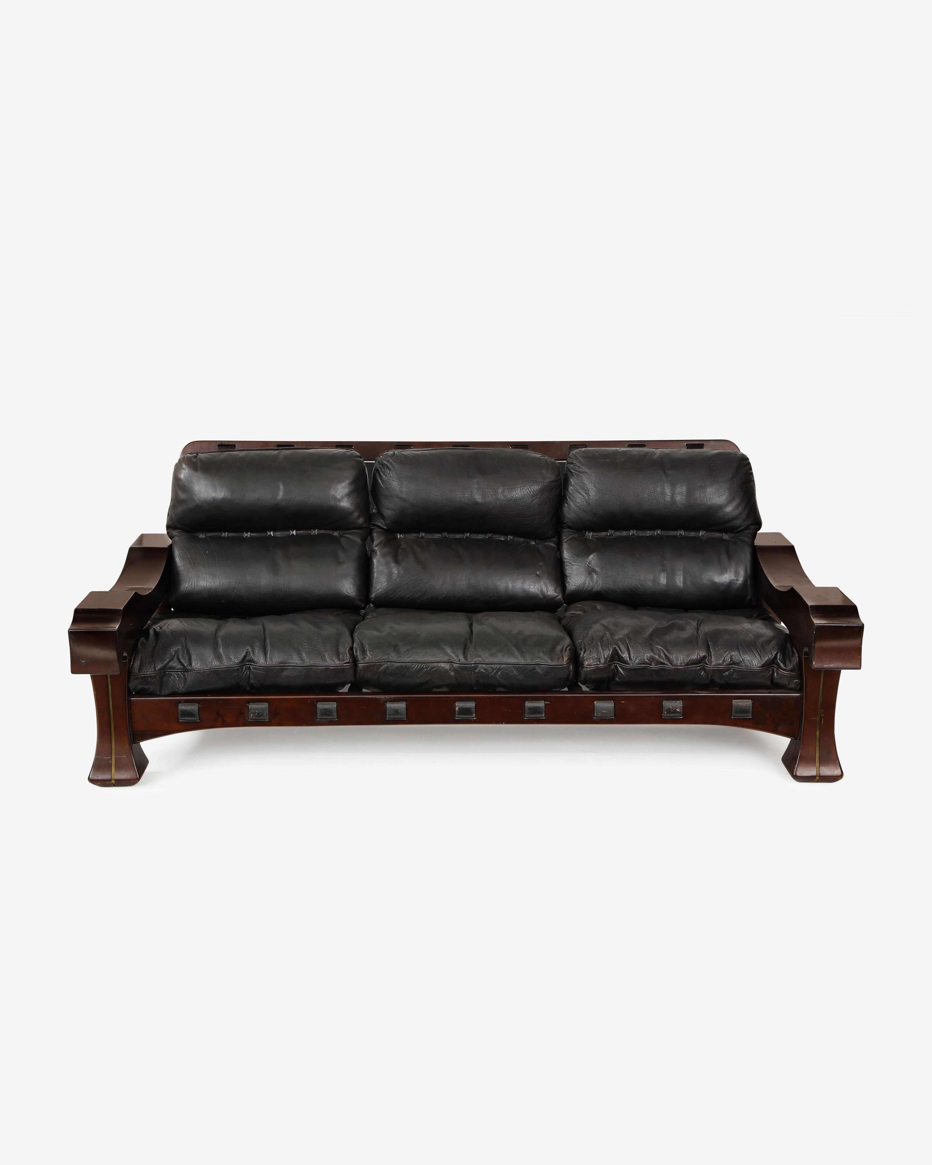 Ussaro sofa by Luciano Frigerio in tropical wood, black leather and brass. These chairs embody the solid and sturdy masculine style emblematic of Frigerio's designs. The mixed media construction of these unique models enhance their esoteric