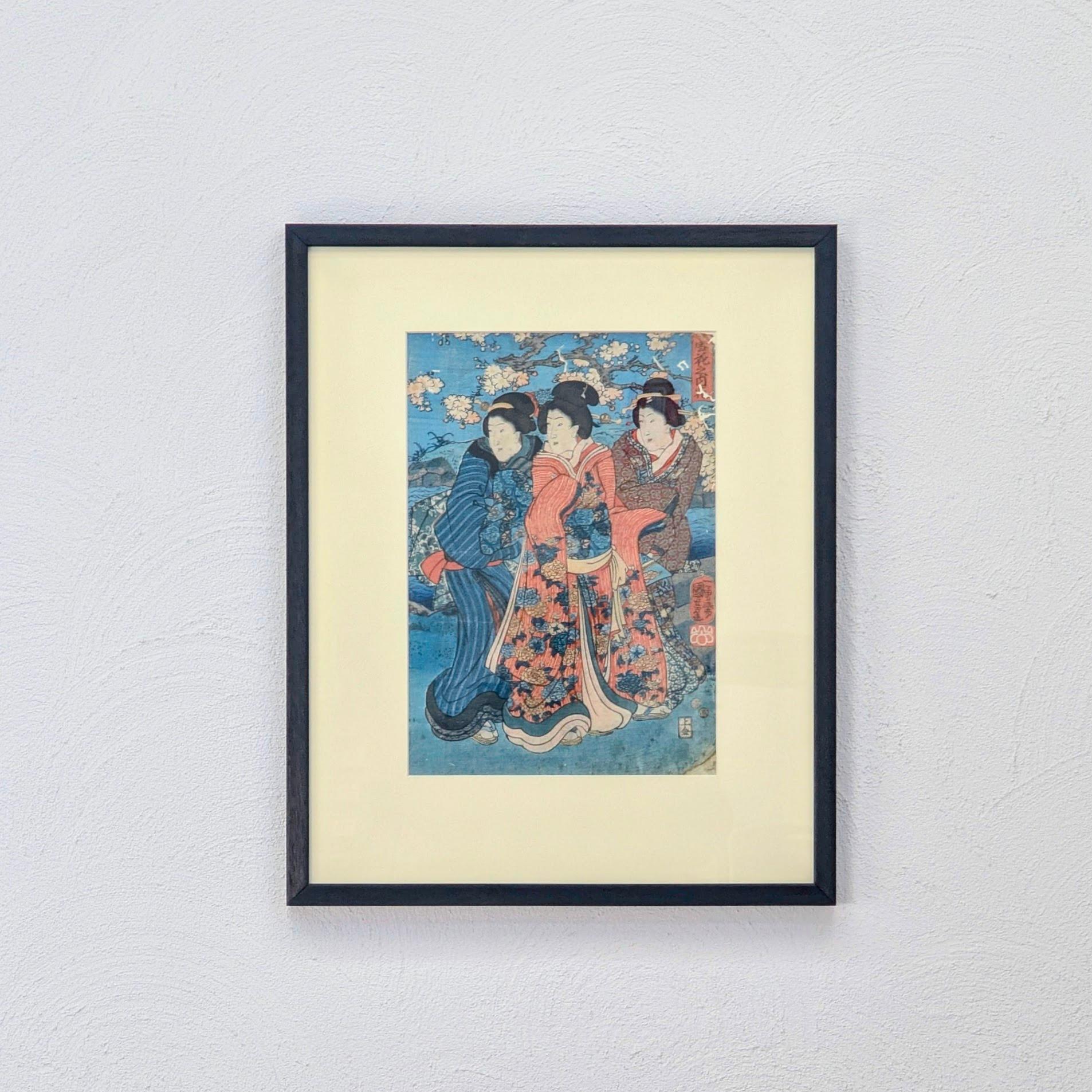 Une exquise gravure sur bois ukiyo-e originale d'Utagawa Kunisada I (Toyokuni III), une force dominante de l'art japonais du XIXe siècle. 

Cette pièce capture trois bijin (beautés) lors d'une sortie printanière, s'arrêtant près d'un plan d'eau sous
