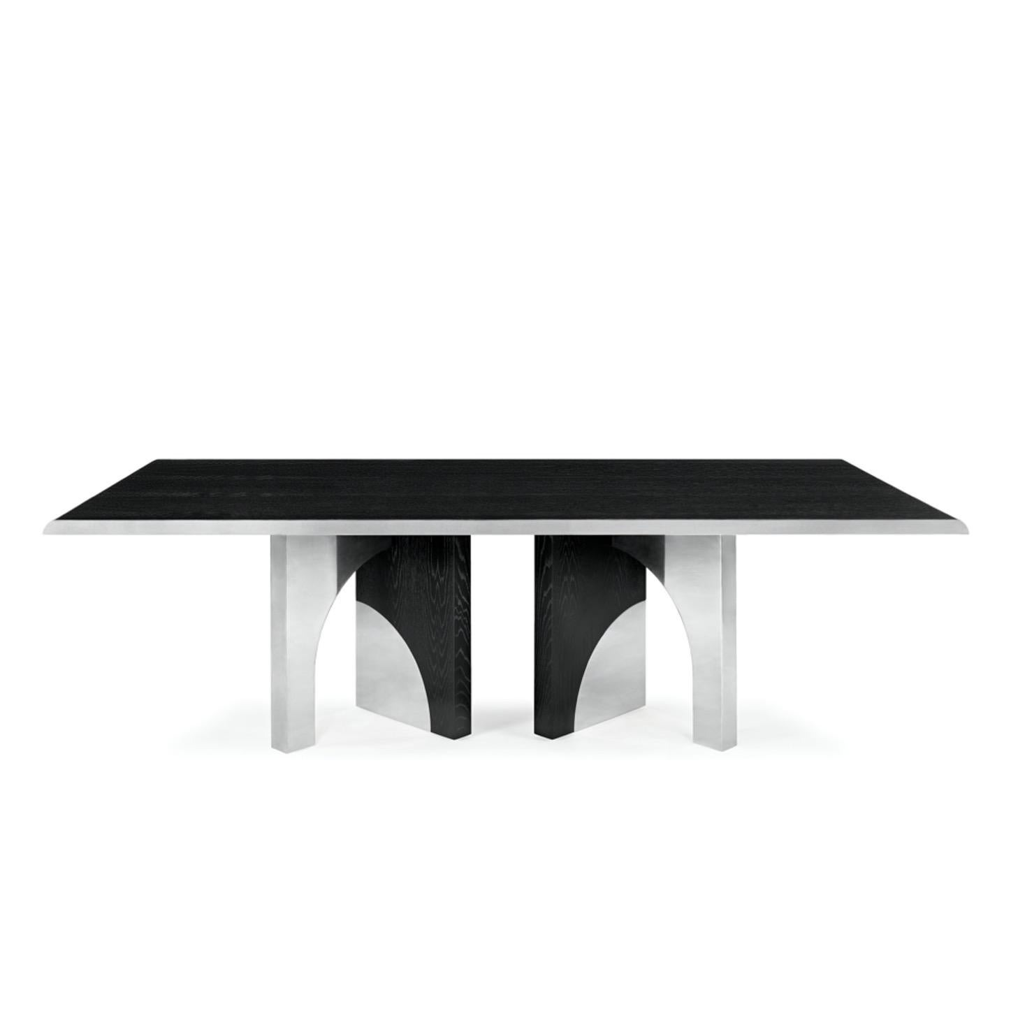 La table à manger Utopia est conçue à l'image de l'échelle architecturale qui suggère une traversée des structures d'une ville utopique, organisée par les principes de symétrie et de formes idéales.
Le design imposant combine le chêne foncé et