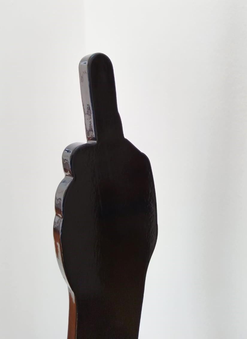 A limited edition, black powder coated mild steel sculpture on a white steel base. The sculpture is typical to Uwe Pfaff's tongue in cheek approach, depicting a human arm showing a middle finger. Edition 2/5. Available in different colours on