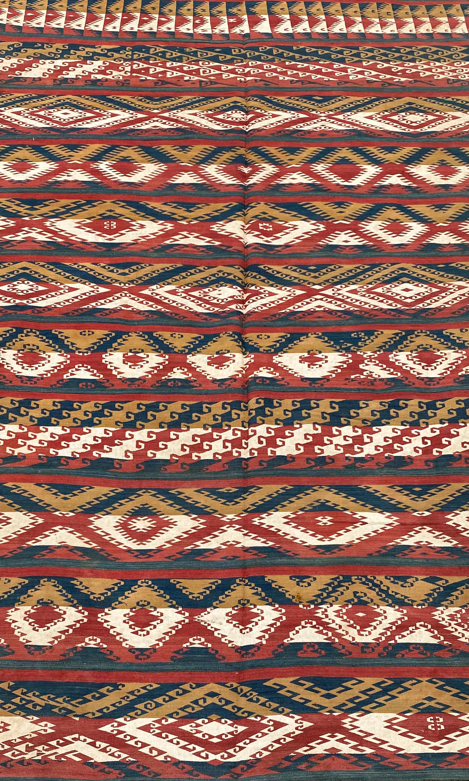 Das dramatische Aussehen dieses antiken usbekischen Ghudjeri-Kilims wird durch die Verwendung von nur vier Farben erreicht: Marineblau, Gelb, Rot und Weiß. Usbekische Ghudjeri sind Kelims, die aus schmalen Harizonalstreifen mit kunstvollen,