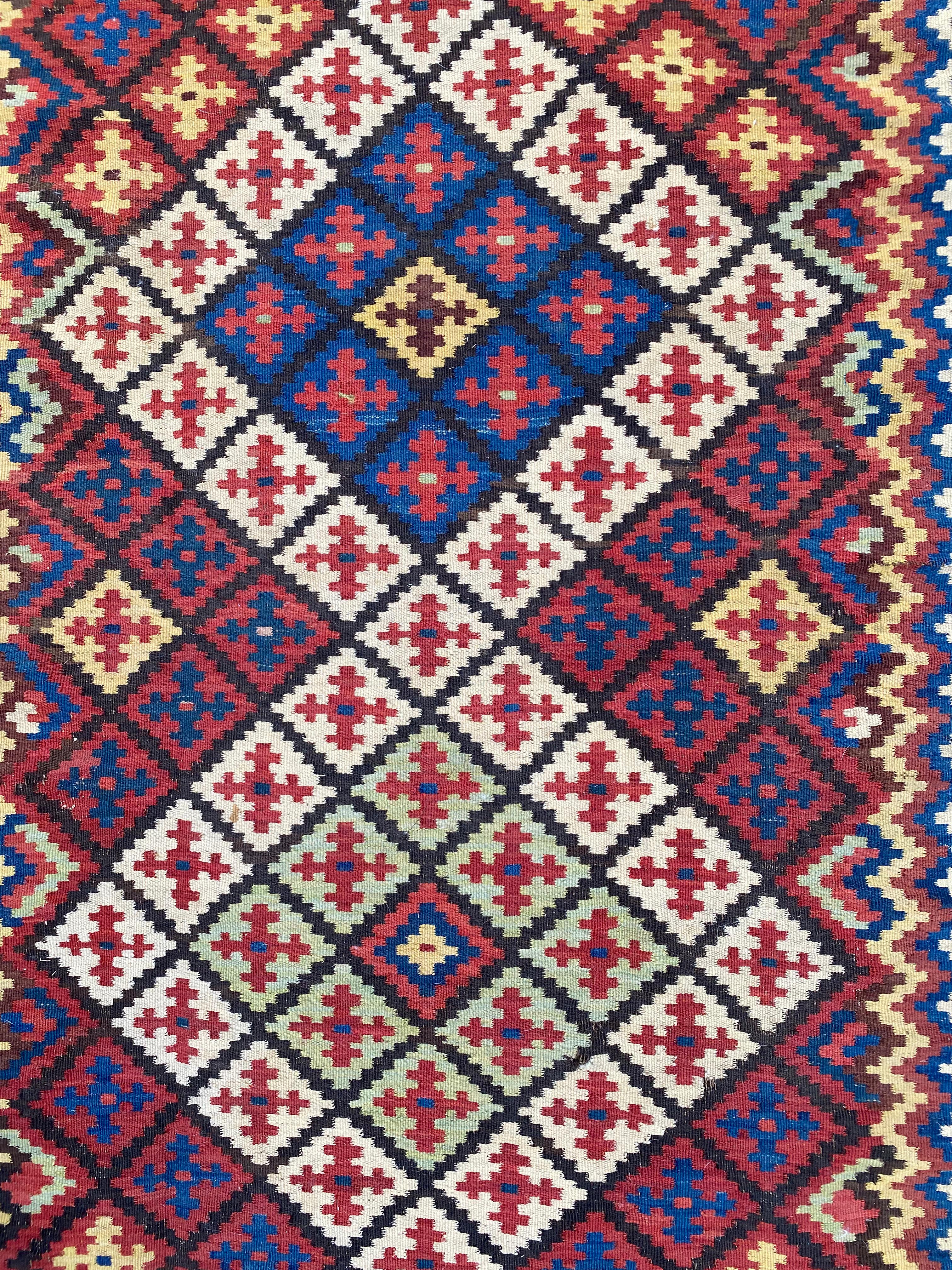 This Antique Uzbekistan Tartari Kilim was crafted from the prolific and diverse Uzbek weavers of Sar-i-Pul. It was crafted using a distinct weave double-interlock technique and employs a grid pattern of diamond shapes. Sar-i-Pul is a town set in the